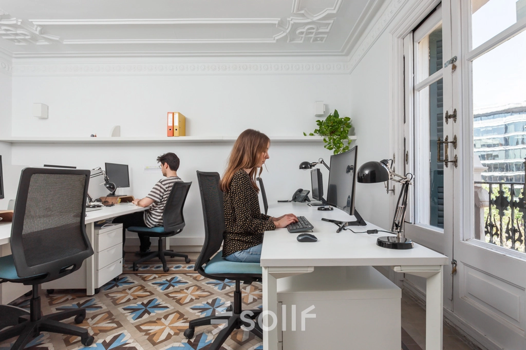 Espacio de trabajo iluminado en alquiler de oficinas en Rambla de Catalunya 125, Barcelona Eixample, con personal trabajando tranquilamente.