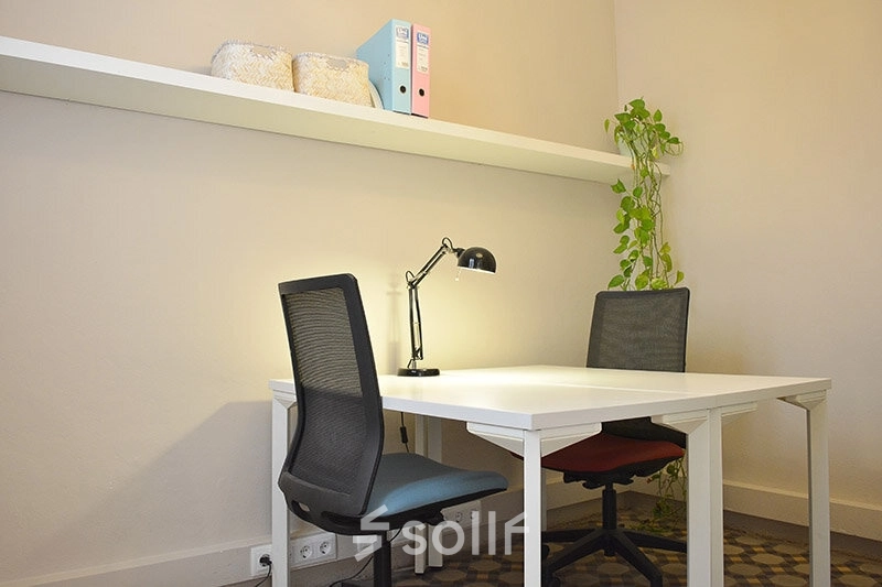 Oficina luminosa y equipada en alquiler de oficinas en Rambla de Catalunya 125, Eixample, Barcelona, con escritorio, sillas y estantería.