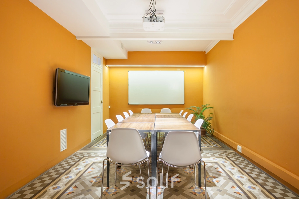 Sala de reuniones luminosa con una gran mesa y sillas metálicas, ideal para alquilar una oficina en Barcelona Eixample, Rambla de Catalunya.
