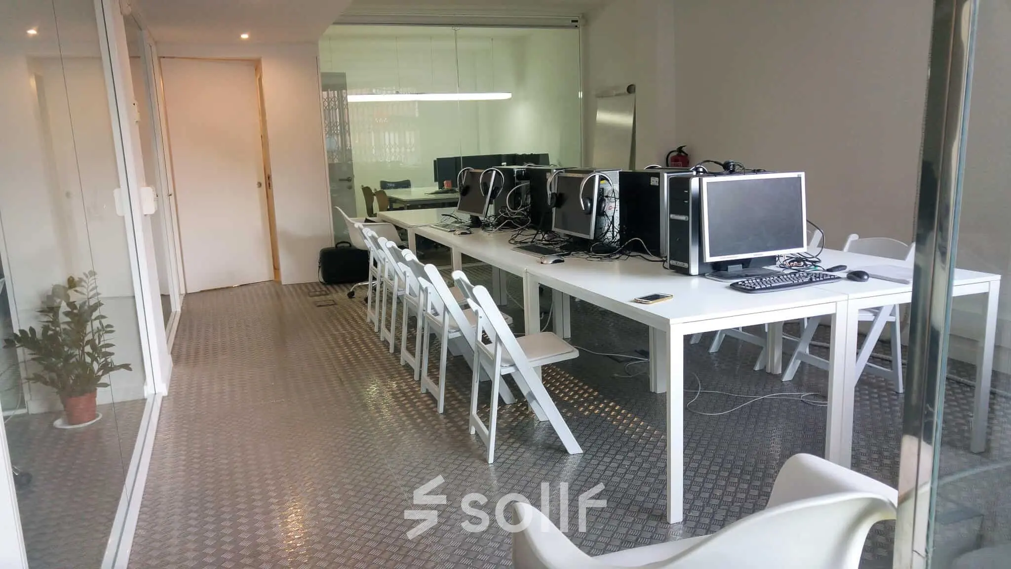 Oficina en Carrer Albigesos 25-27, Barcelona Gràcia, con mesas largas, computadoras y sillas blancas, ideal para alquilar una oficina.