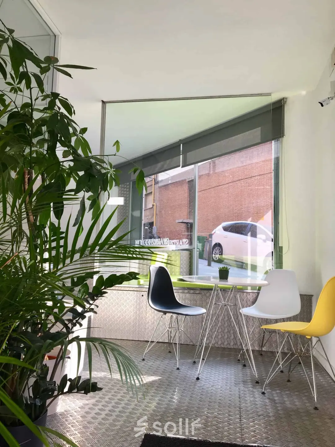 Sala de recepción en Carrer Albigesos 25-27, Barcelona Gràcia, con sillas modernas y una ventana amplia, ideal para quienes buscan alquilar una oficina con luz natural.