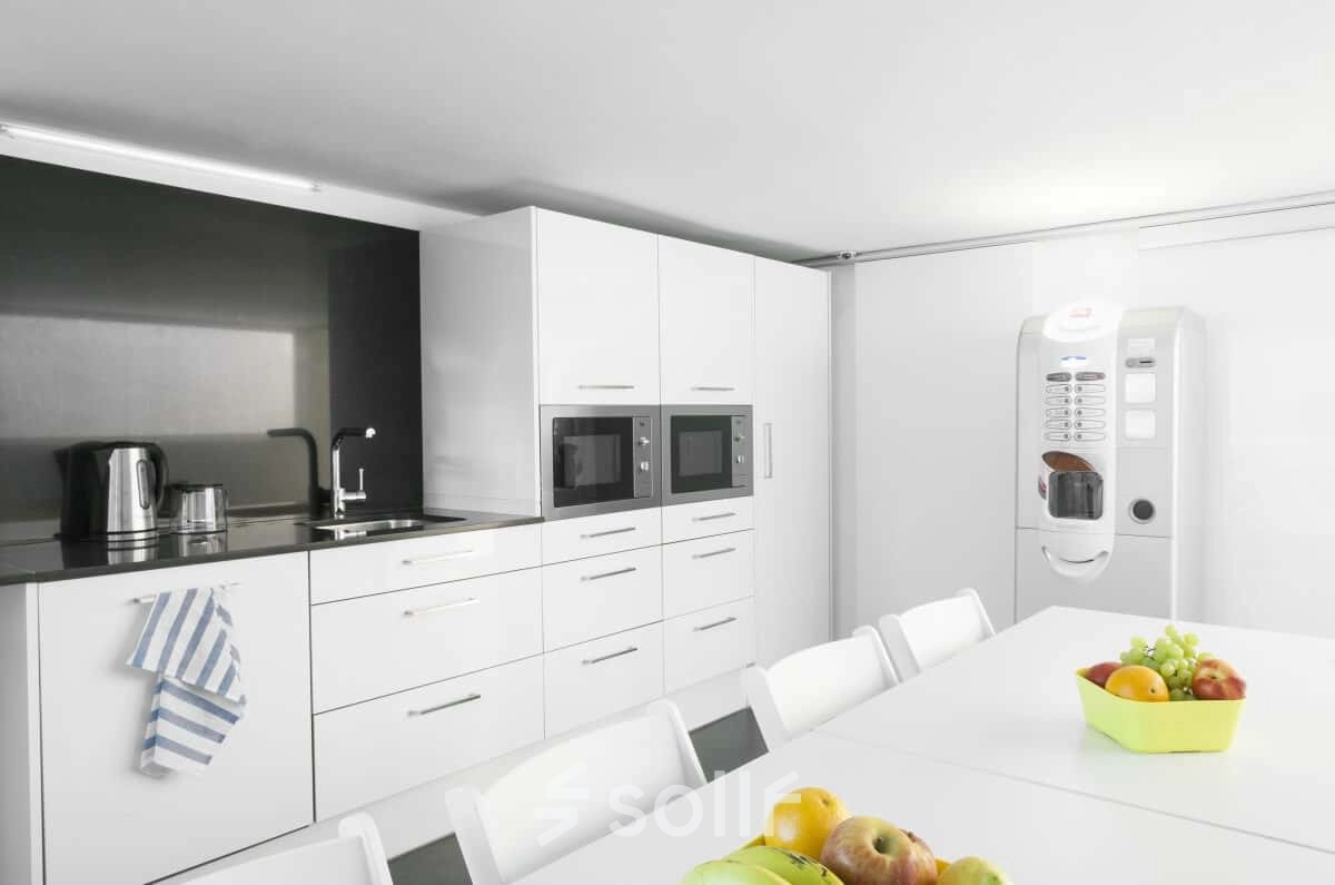 Cocina moderna y luminosa perfecta para alquilar una oficina en Carrer de L'Escorial 180, Barcelona Gràcia, con mesa blanca y electrodomésticos.