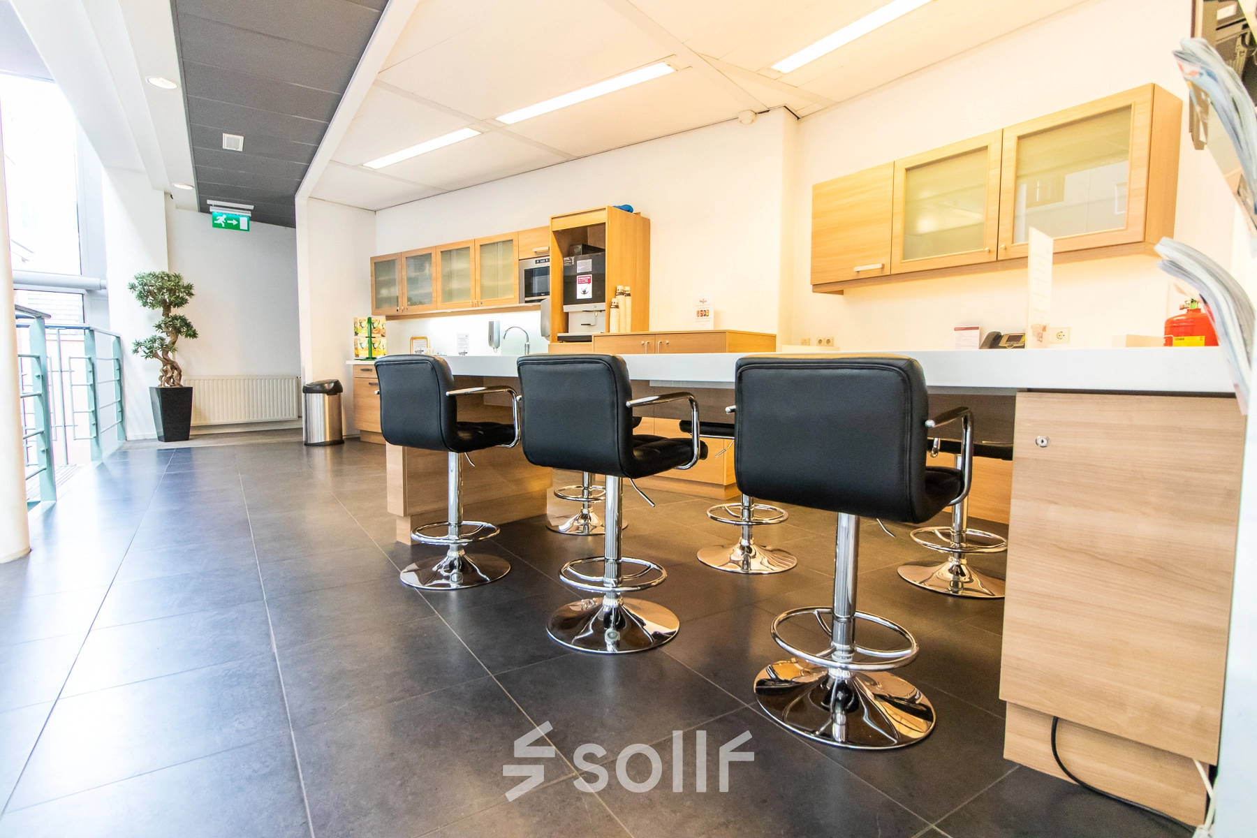 Espacio de oficina moderno en Madrid Arganzuela, Calle de Méndez Álvaro 20, ideal para alquilar una oficina, equipado con mesas, sillas y un área de cocina contemporánea.