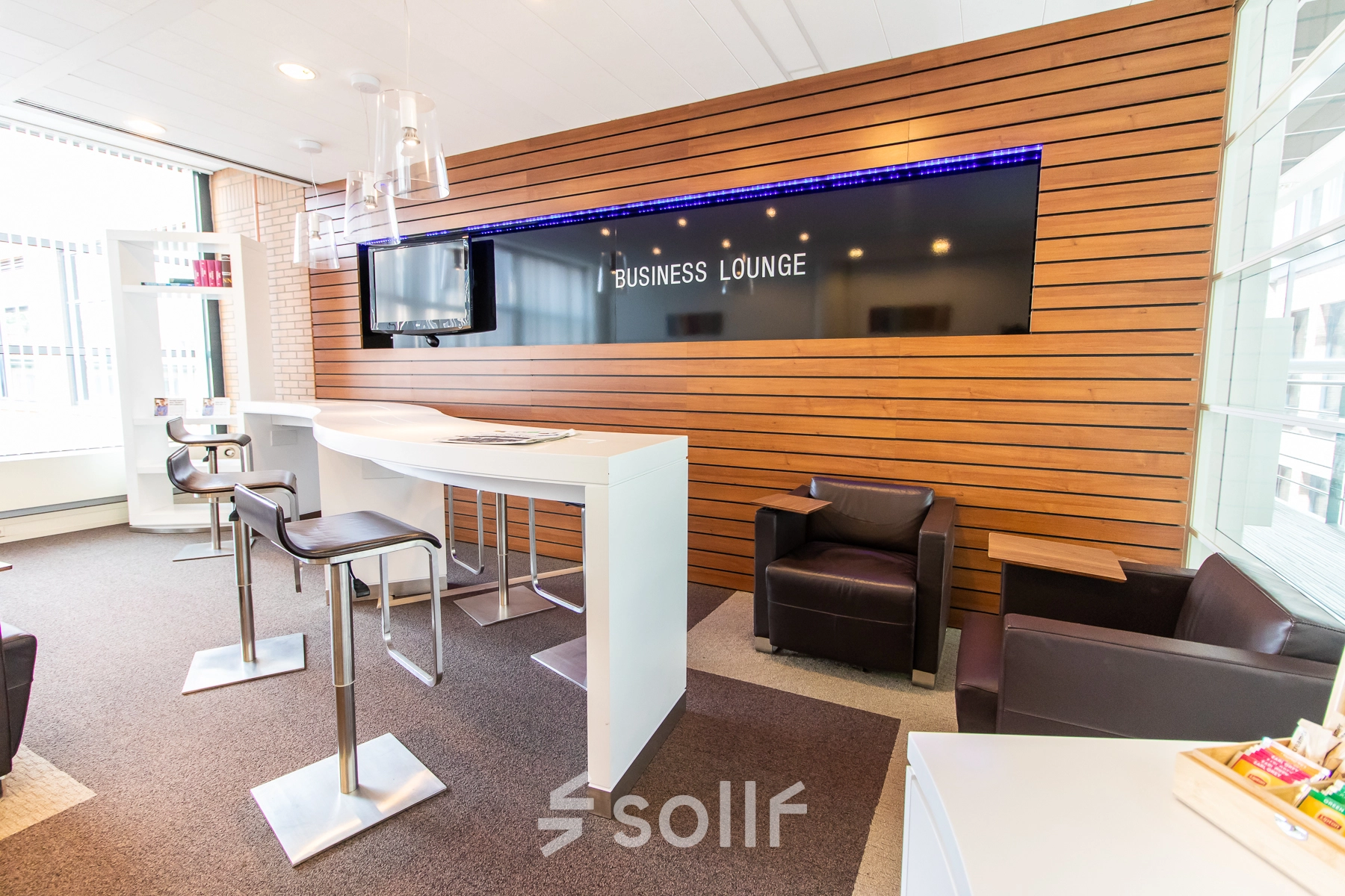 Moderna área de lounge en oficina de alquiler en Calle de Méndez Álvaro 20, Madrid Arganzuela, con asientos cómodos y televisor para reuniones informales.