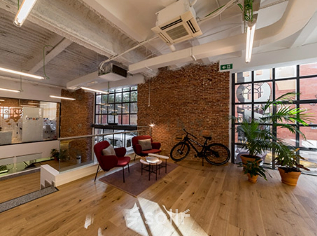 Espaciosa oficina en Manzanares 4, Madrid Centro, ideal para alquilar una oficina. Con diseño moderno, pisos de madera, y plantas decorativas, ofrece un ambiente acogedor.