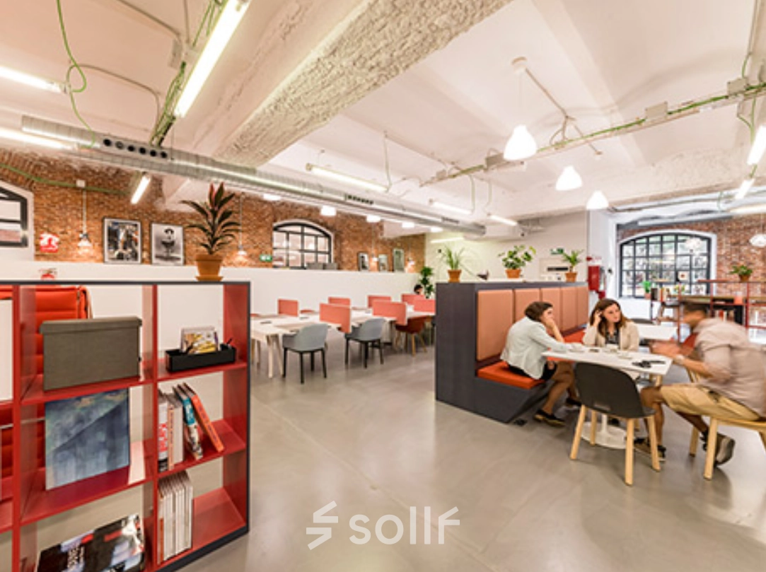 Espacio de trabajo compartido con mesas y sillas en alquiler de oficinas en Manzanares 4, Madrid Centro, con personas colaborando en proyectos.