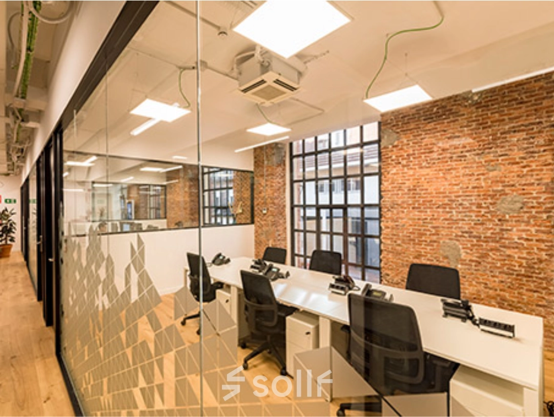 Espacio de alquiler de oficinas en Manzanares 4, Madrid Centro, con mesas y sillas modernas en un entorno luminoso con paredes de ladrillo visto.