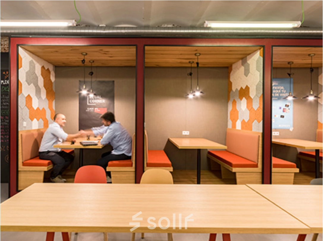 Oficinas en Manzanares 4, Madrid Centro, con espacios compartidos modernos para alquilar. Dos personas colaboran en un área de trabajo con decoración cálida y contemporánea.
