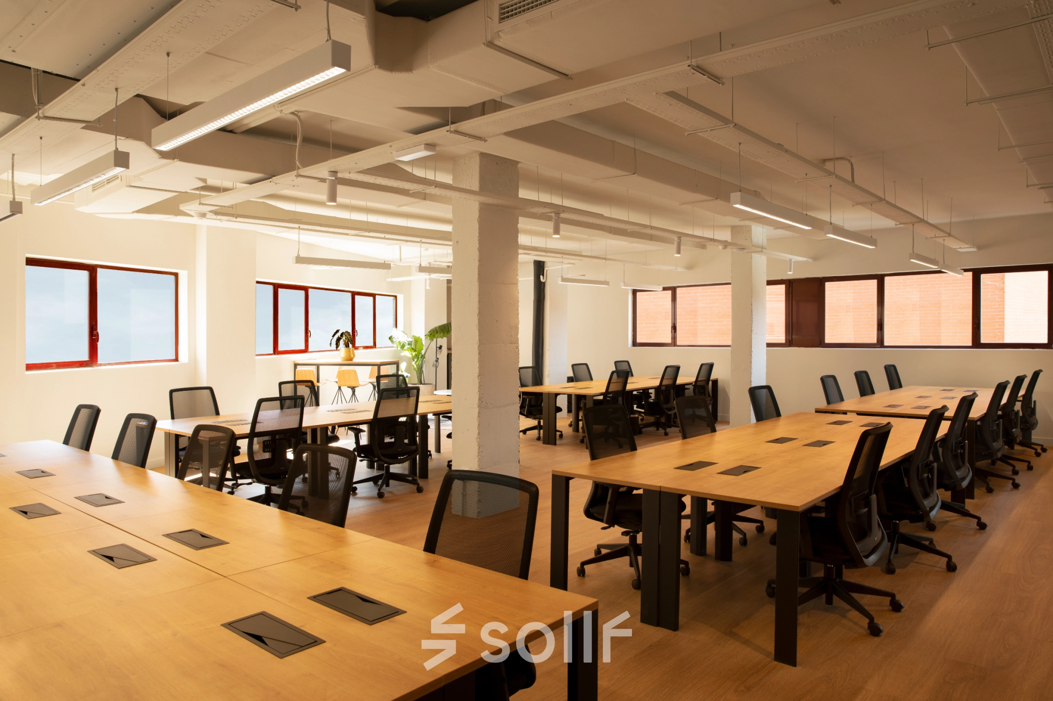 Vista de un espacio de alquiler de oficinas luminoso y espacioso en Paseo Imperial 14, Madrid Centro, con mesas de trabajo y sillas ergonómicas.