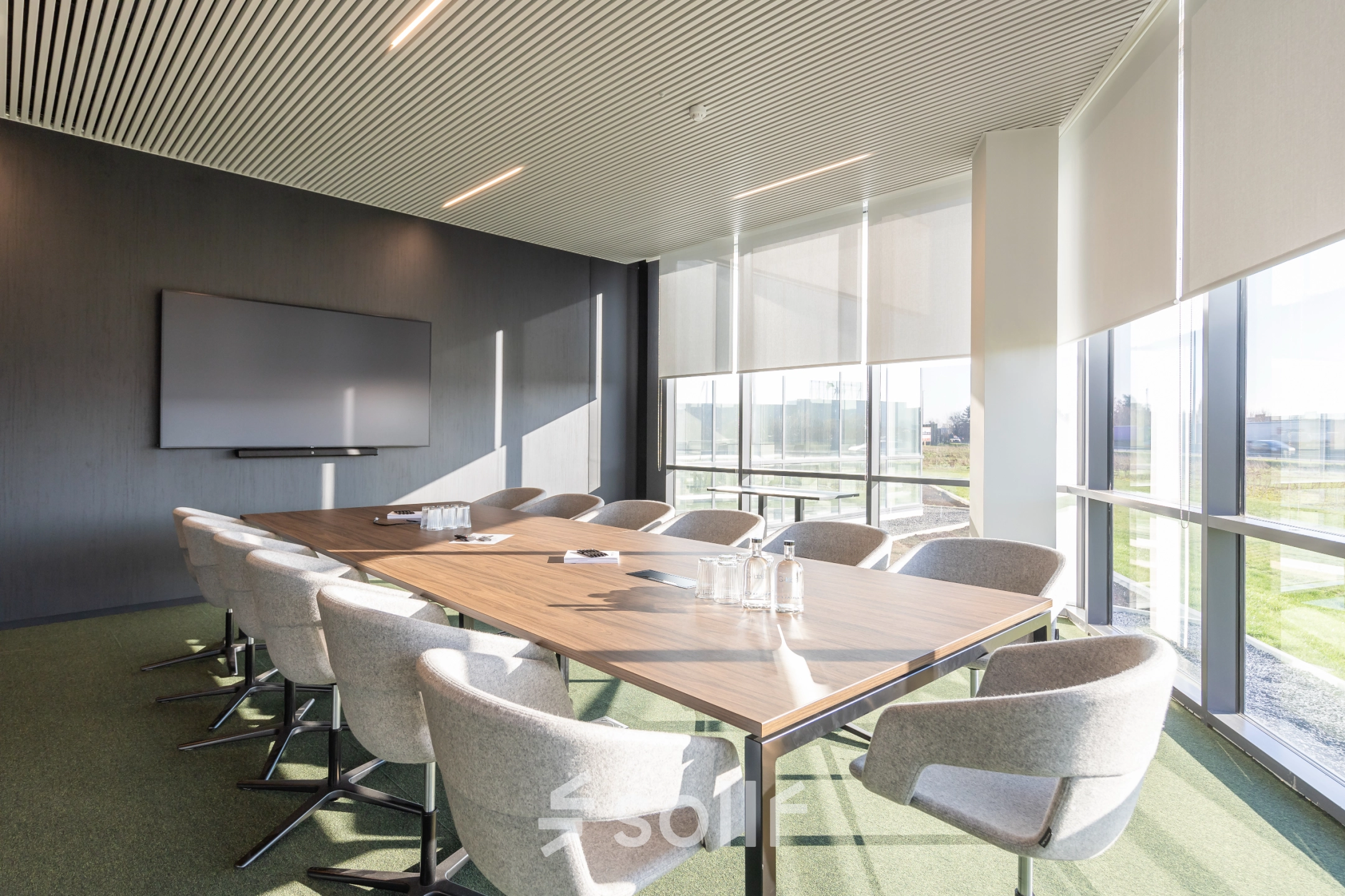 Moderne vergaderruimte in een kantoorpand op Korte Keppestraat 19, Aalst, met een grote vergadertafel, comfortabele stoelen en veel natuurlijk licht. Ideaal voor kantoorruimte huur.