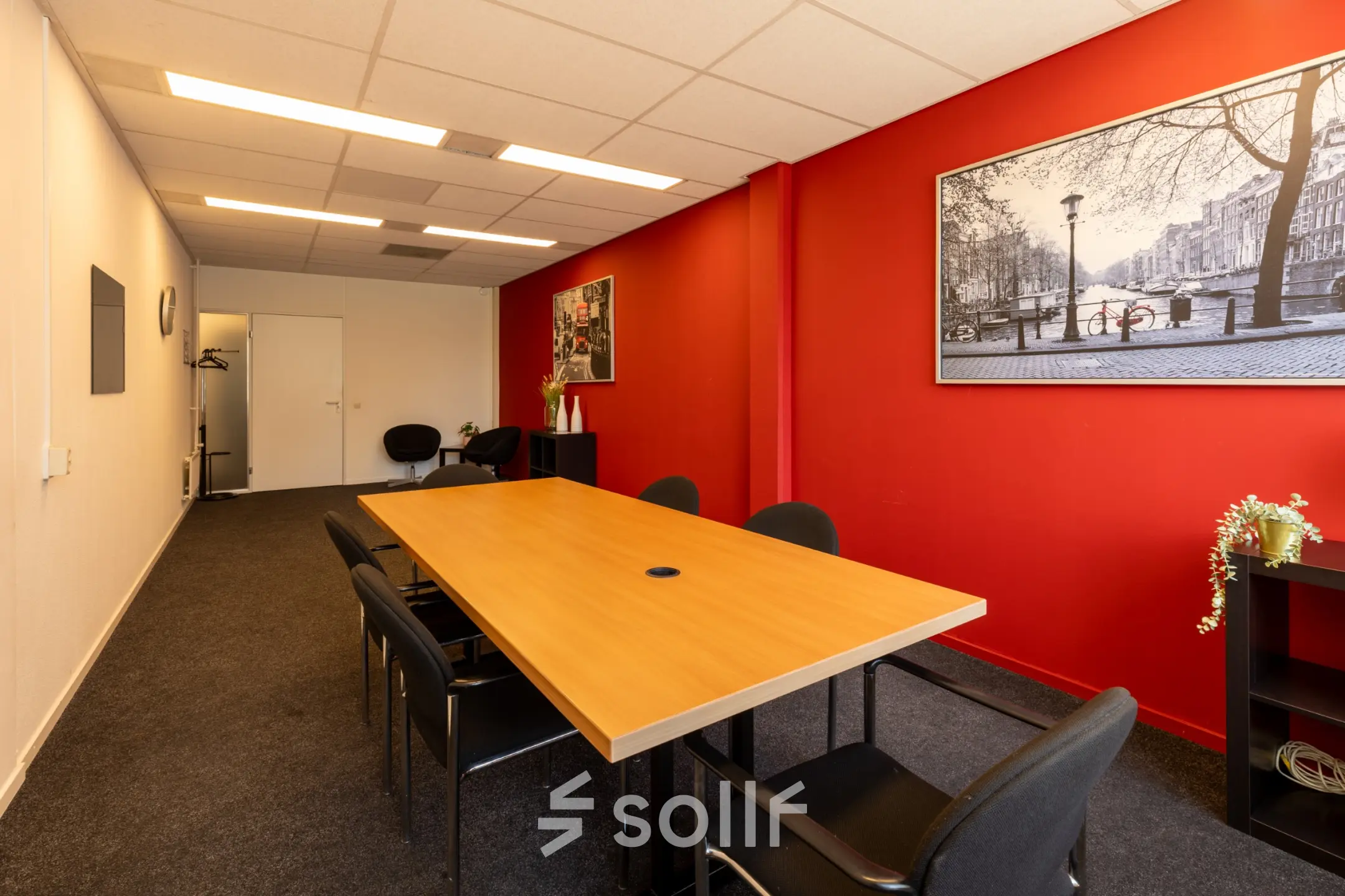 Vergaderruimte in kantoorpand Bedrijvenpark Twente 305, Almelo, met rode muur en houten tafel omringd door stoelen. Ideaal voor kantoorruimte huren.