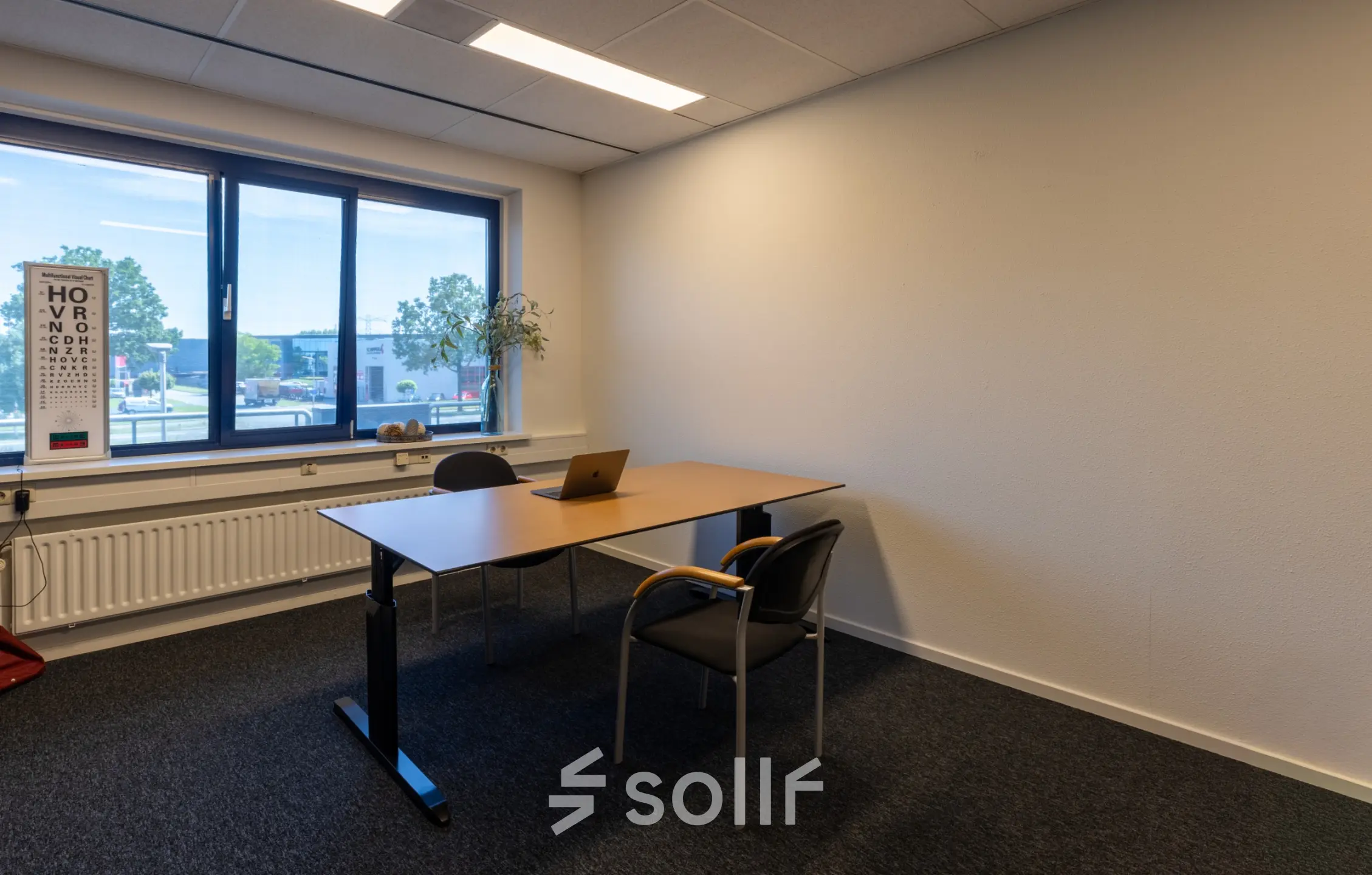 Kantoorruimte te huur in Almelo, gelegen op Bedrijvenpark Twente 305 met een eenvoudig bureau en stoelen, geschikt voor één of twee personen met uitzicht op bedrijventerrein.
