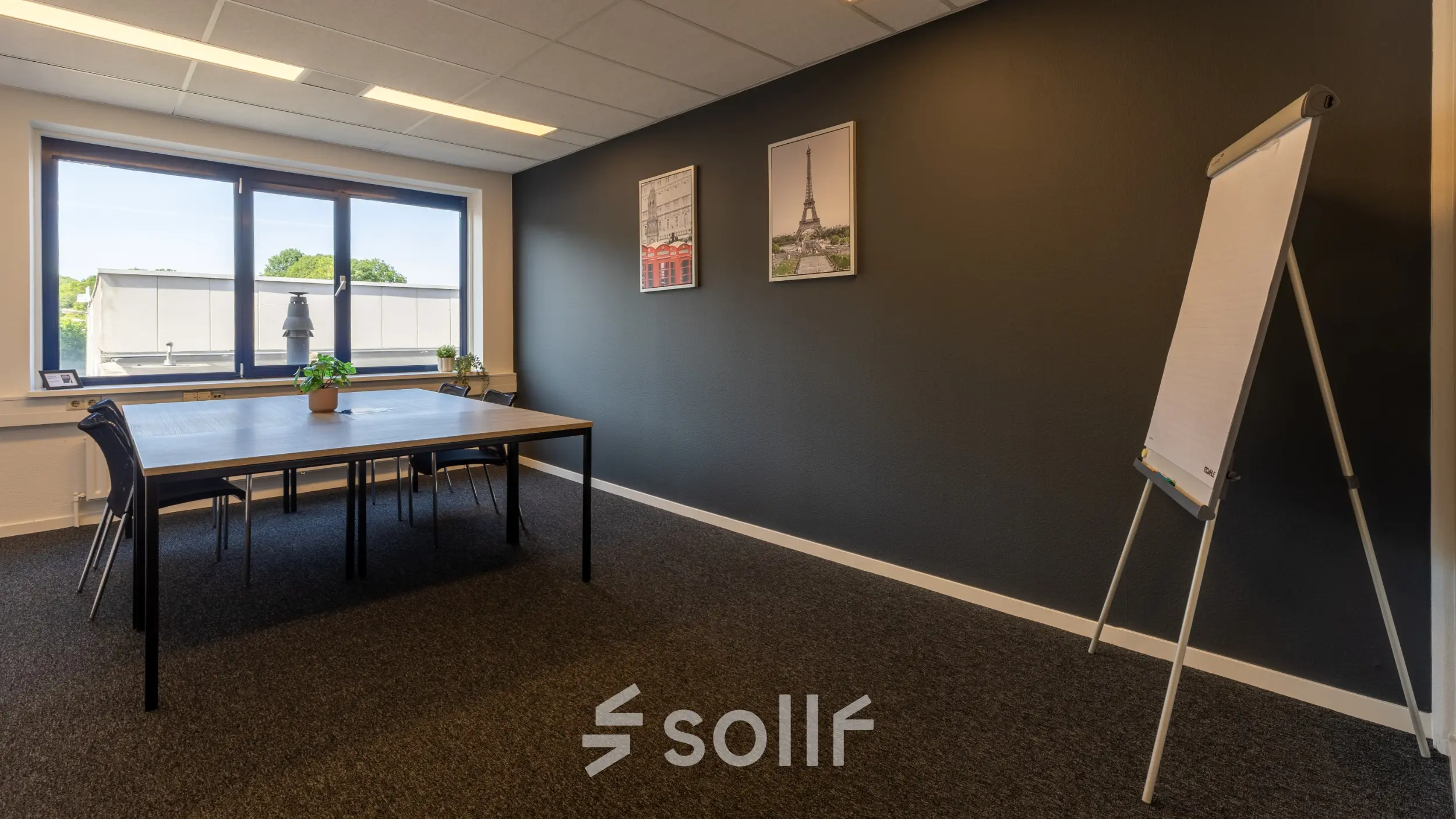 Ruime kantoorruimte te huur in Almelo met grote tafel en stoelen, voorzien van natuurlijk licht en inspirerende wanddecoratie.