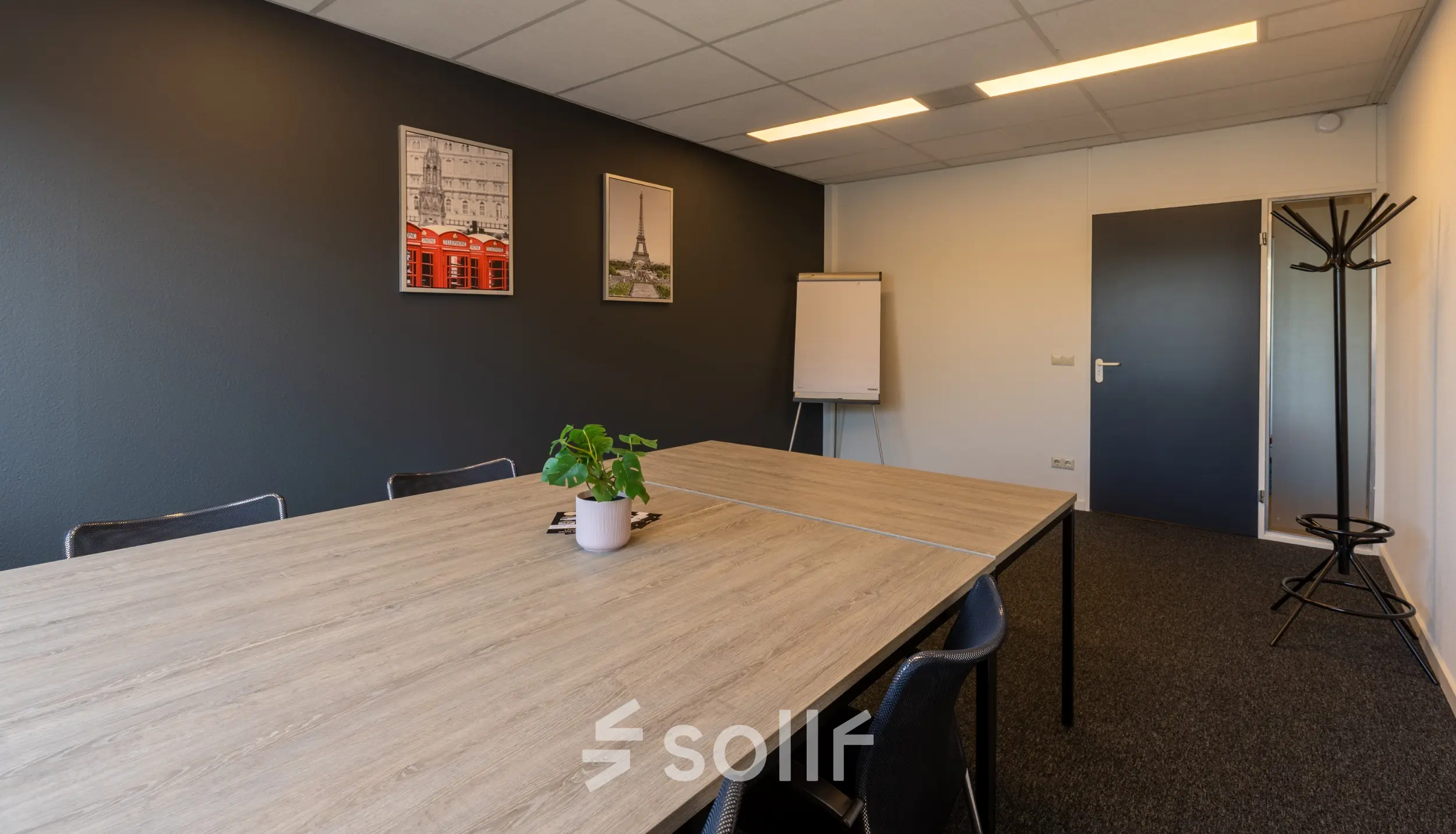 Kantoorruimte huren op Bedrijvenpark Twente 305 in Almelo met een moderne vergaderruimte, gedecoreerde muren en een houten tafel met stoelen.