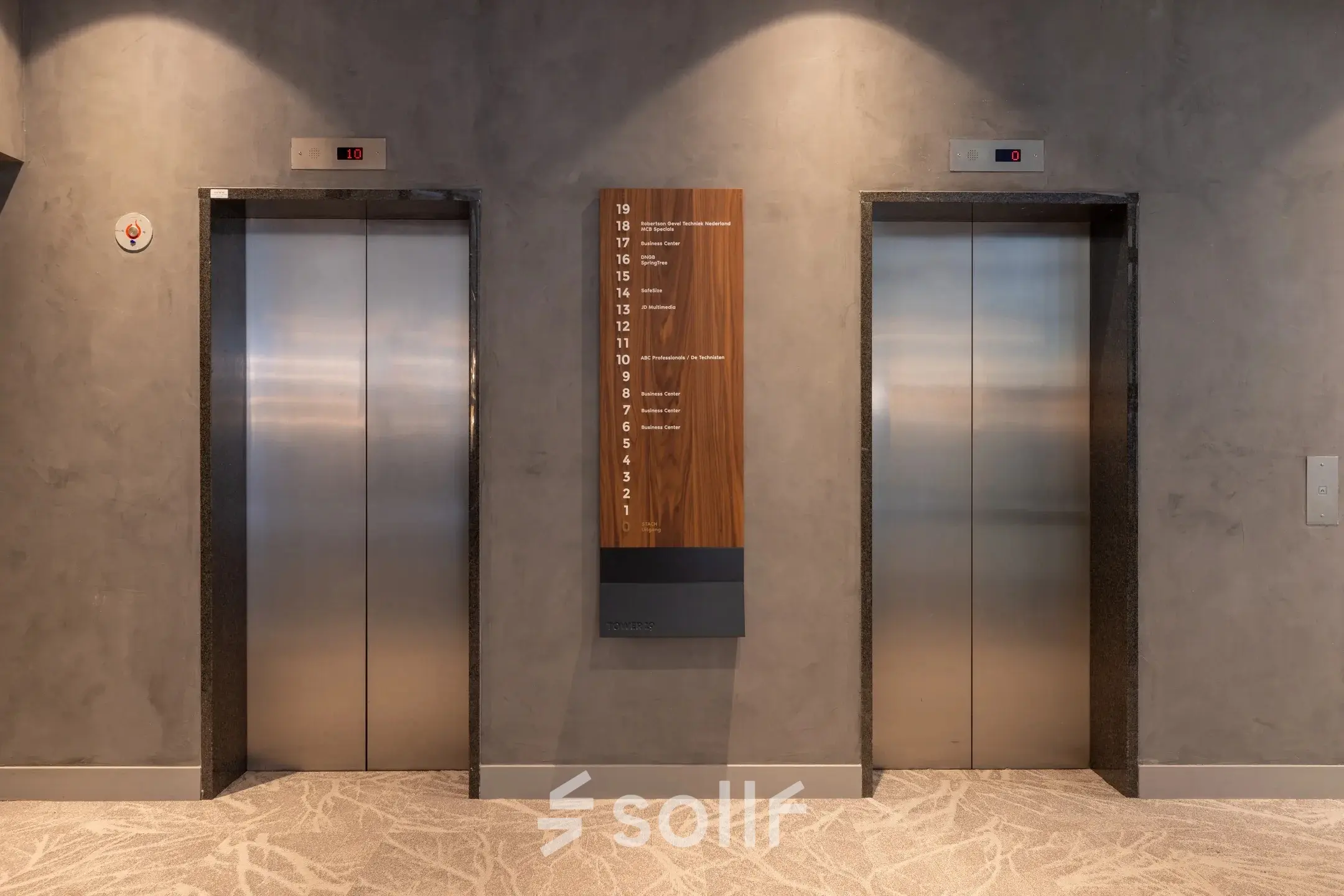 Liftlobby in kantoorpand op Landdrostdreef 124, Almere Stad. Twee liften met een moderne uitstraling en een bord met verdiepingsnummers. Voorzien van subtiele verlichting.