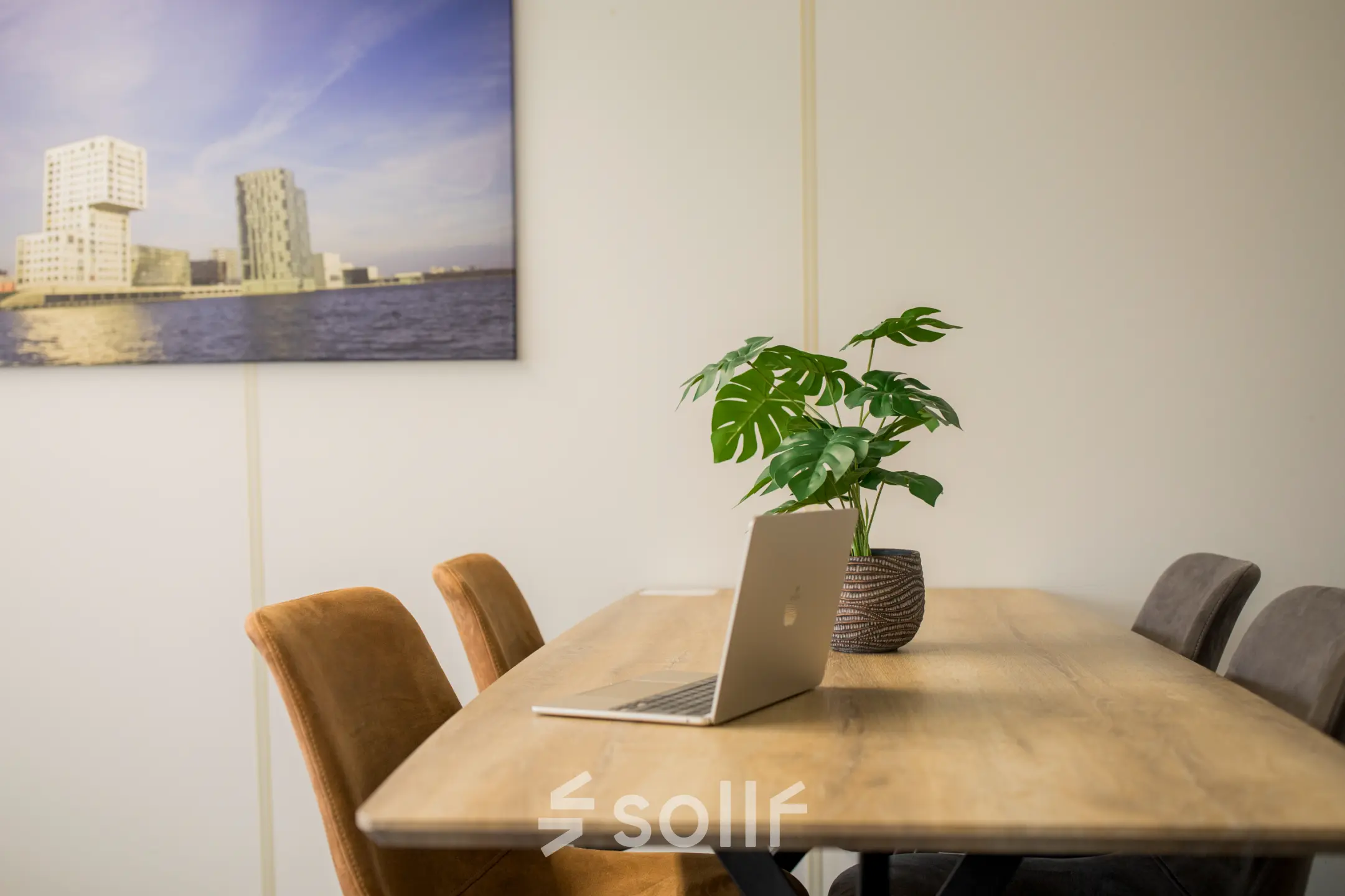 Kantoorruimte huren in Almere Stad aan Markerkant 1310 met een tafel, stoelen, een laptop en een plant. De muren zijn voorzien van fotokunst.