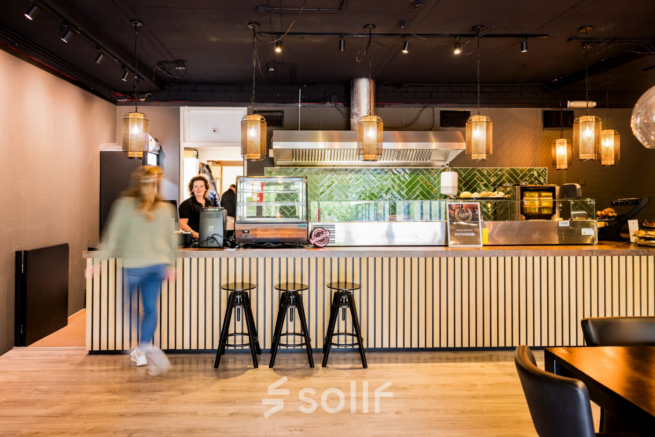 Moderne kantoorruimte in Almere Stad bij Markerkant 1310, met een stijlvolle gemeubileerde lounge met industrieel interieur, ideaal voor pauzes. Personeel serveert koffie aan de bar.