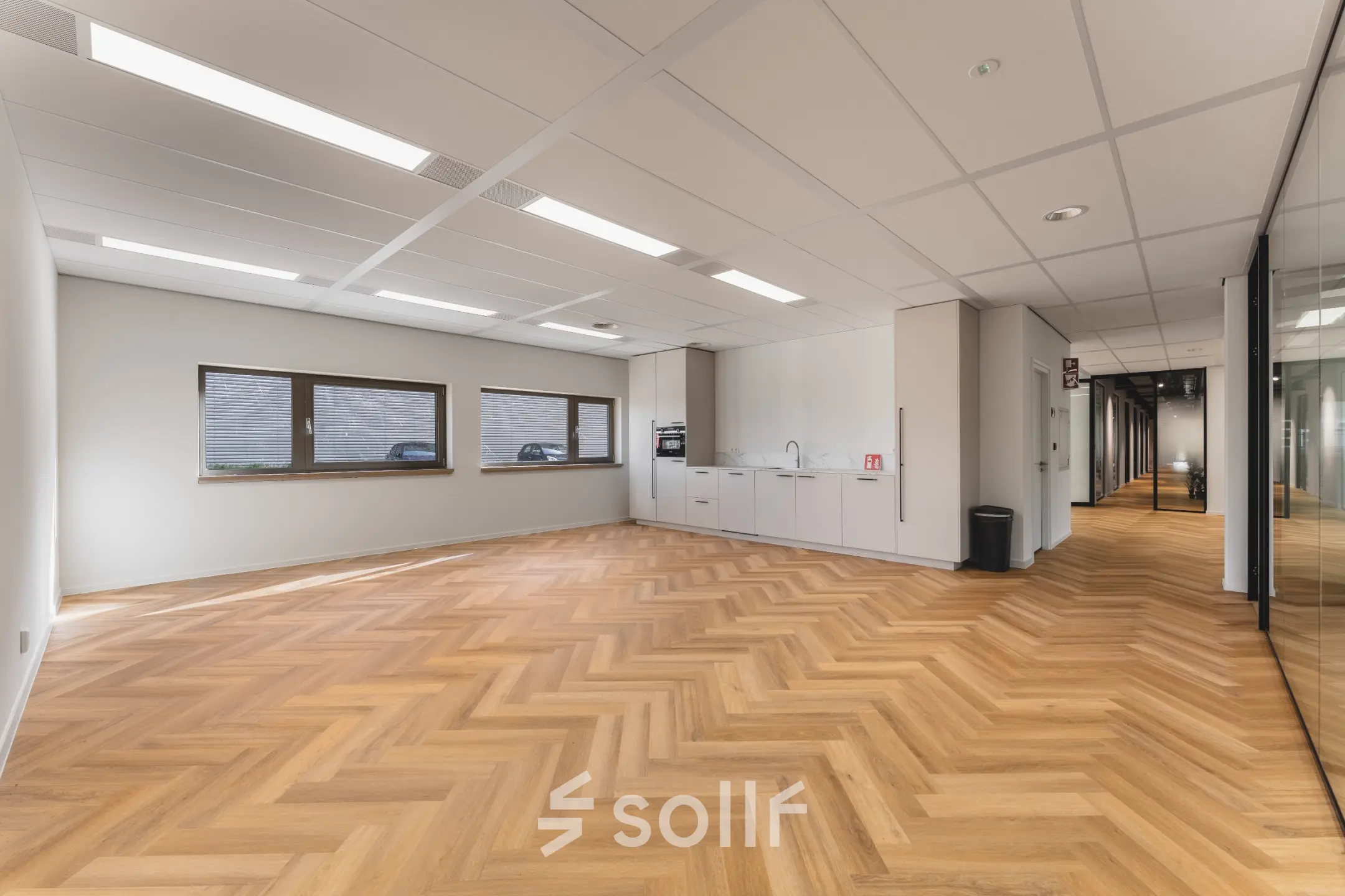 Lichte kantoorruimte op Veluwezoom 15 in Almere Stad met visgraat houten vloer, ingebouwde keuken en grote ramen. Ideaal voor wie een kantoorruimte wil huren.
