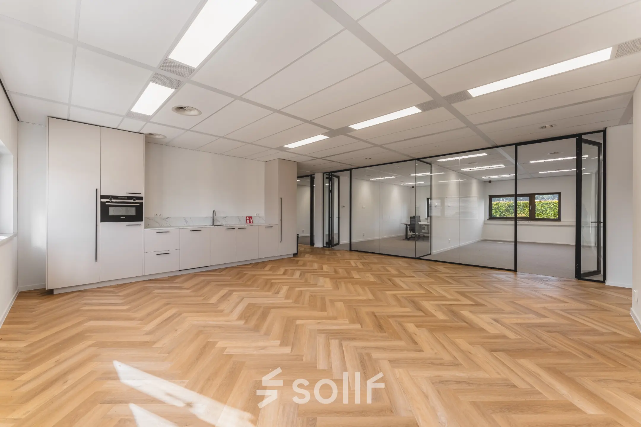 Kantoorruimte op Veluwezoom 15 in Almere Stad met een houten vloer, glazen wanden en een ingebouwde pantry. Ideaal voor wie een lichte werkplek wil huren.