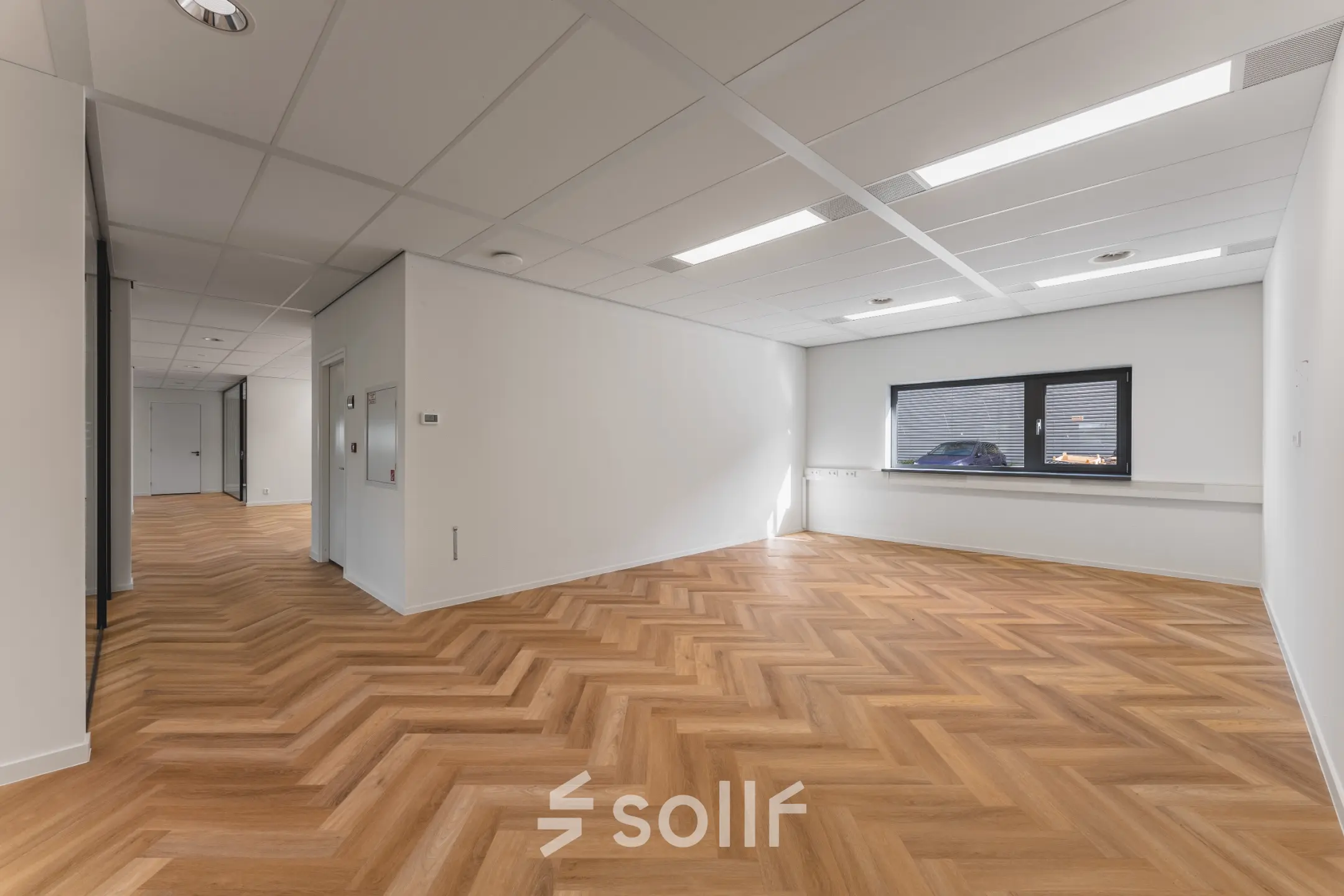 Ruime kantoorruimte met een houten visgraatvloer en veel natuurlijk licht dankzij een groot raam. Ideaal voor bedrijven die kantoorruimte willen huren aan de Veluwezoom 15 in Almere Stad.