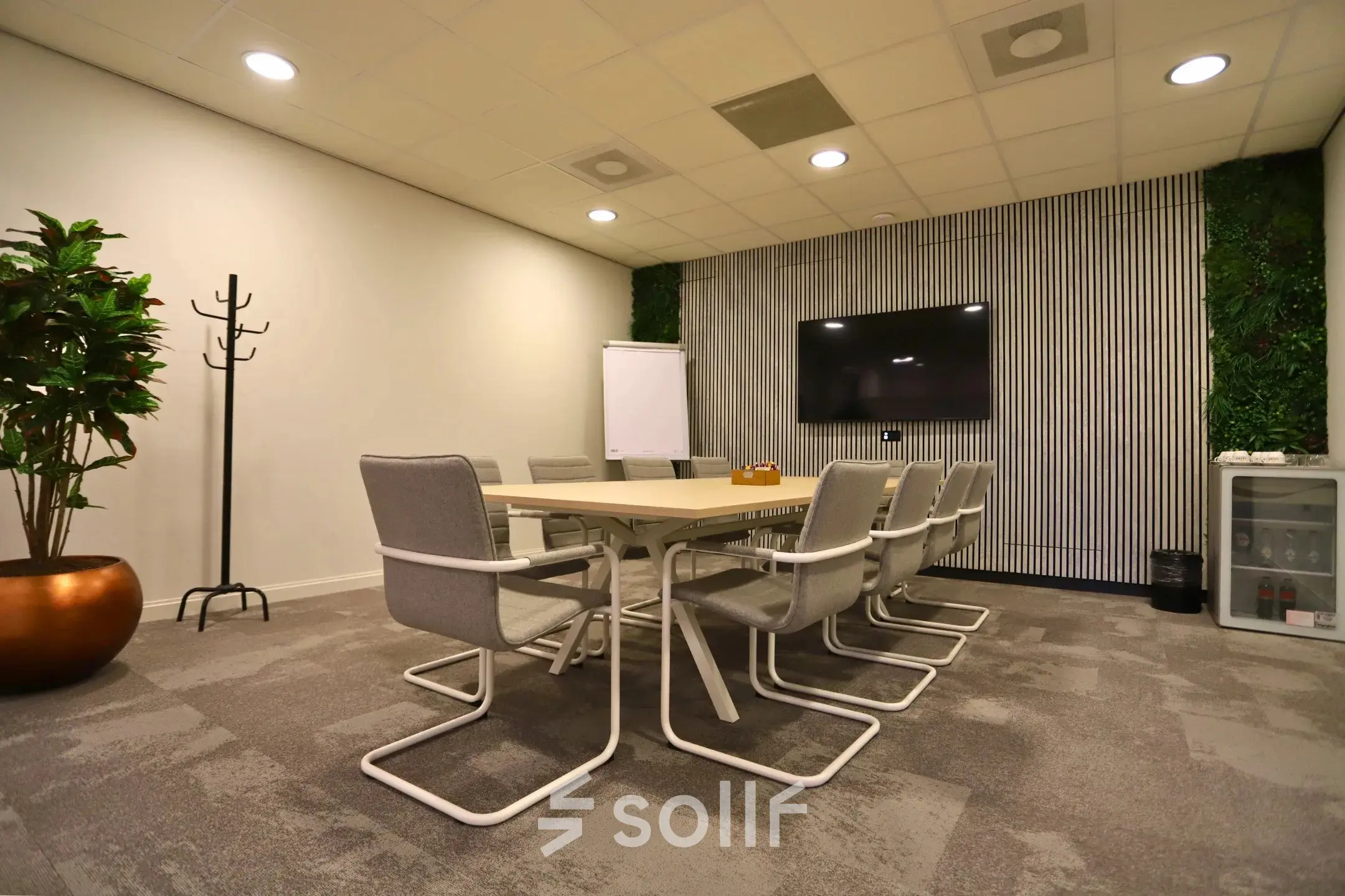 Moderne vergaderruimte in kantoorpand Leidse Schouw 2, Alphen aan den Rijn, met groot scherm, tafel en stoelen. Ideale plek om kantoorruimte te huren voor meetings. Groenaccenten en flip-over aanwezig.
