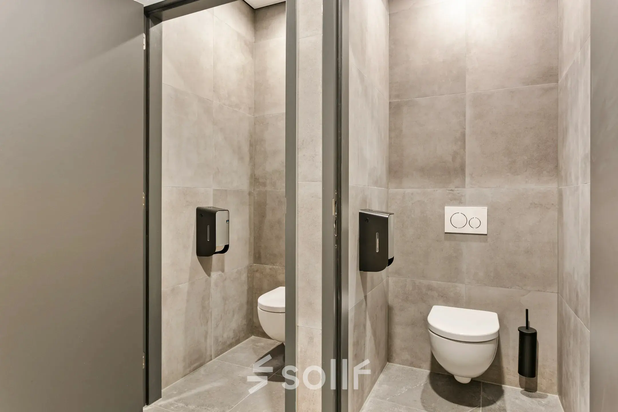 Twee moderne toiletcabines in een kantoorpand op Astronaut 28 in Amersfoort Calveen met grijze tegels.
