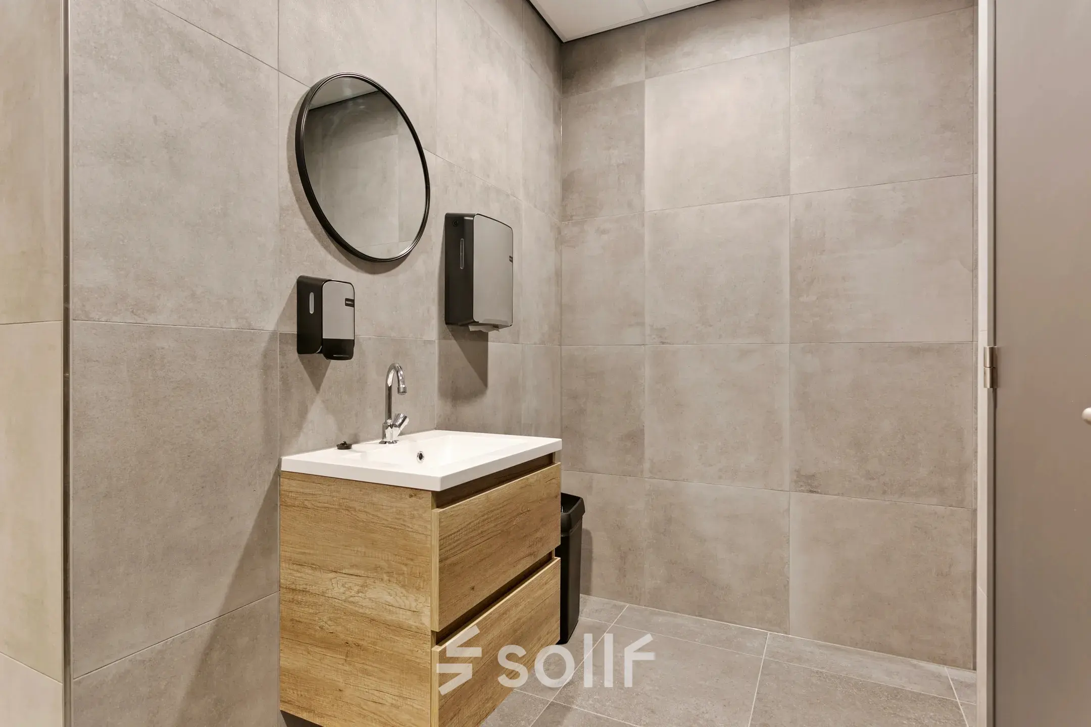 Moderne kantoorruimte huren in Amersfoort Calveen met strakke badkamerinrichting op Astronaut 28, compleet met wastafel, ronde spiegel en beige wandtegels.