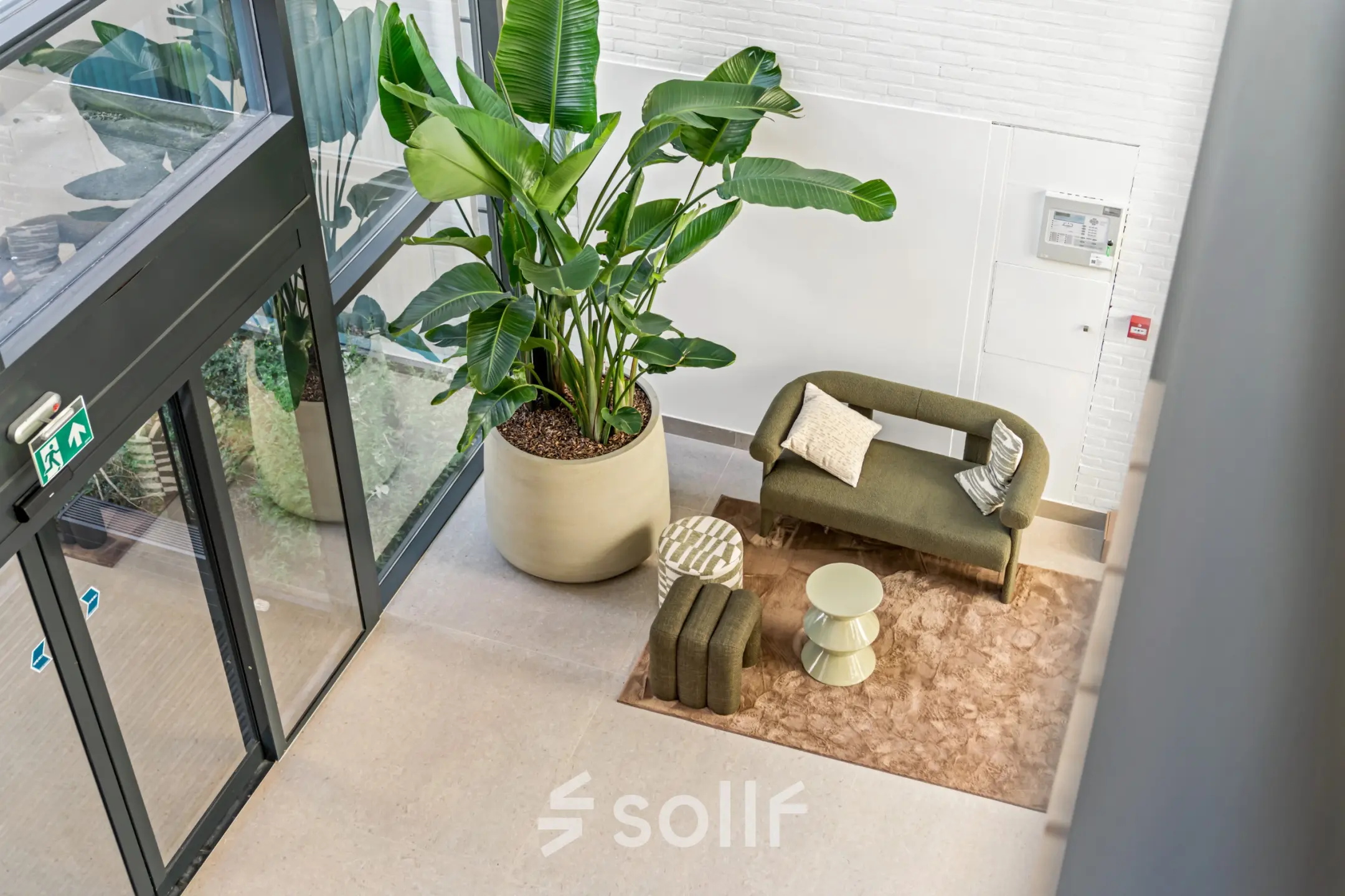 Entree van een kantoorpand op Maanlander 43 in Amersfoort Calveen met een stijlvolle loungehoek en grote groene planten.