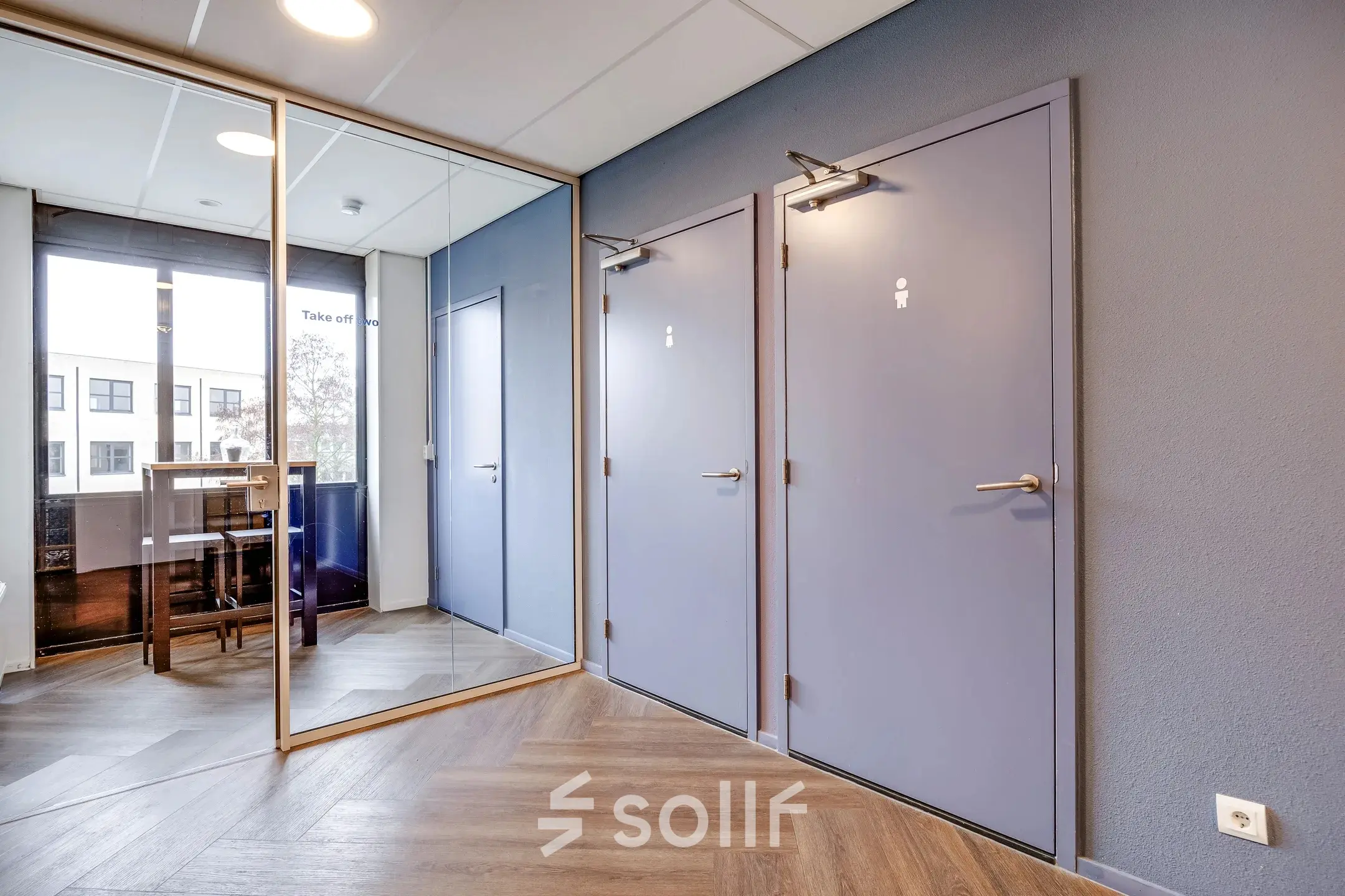 In het kantoorpand op Maanlander 47 in Amersfoort Calveen zijn twee deuren naar het toilet te zien, met spiegels en een hoge tafel in de achtergrond.