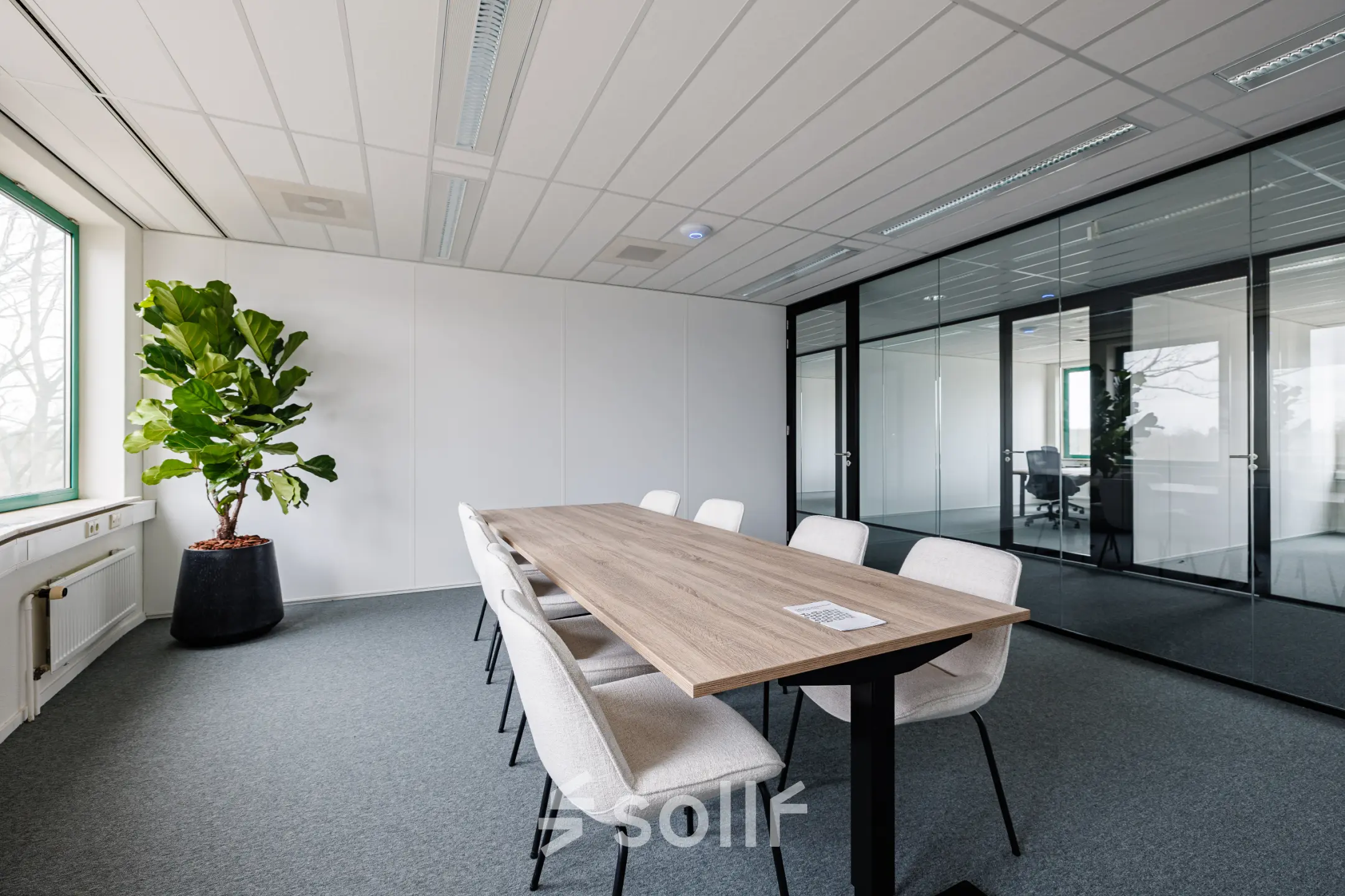Lichte kantoorruimte met moderne vergadertafel en stoelen bij Stadsring 201 in Amersfoort Centrum. Glaswanden bieden uitzicht op andere kantoorruimten. Perfecte locatie om een kantoorpand te huren.