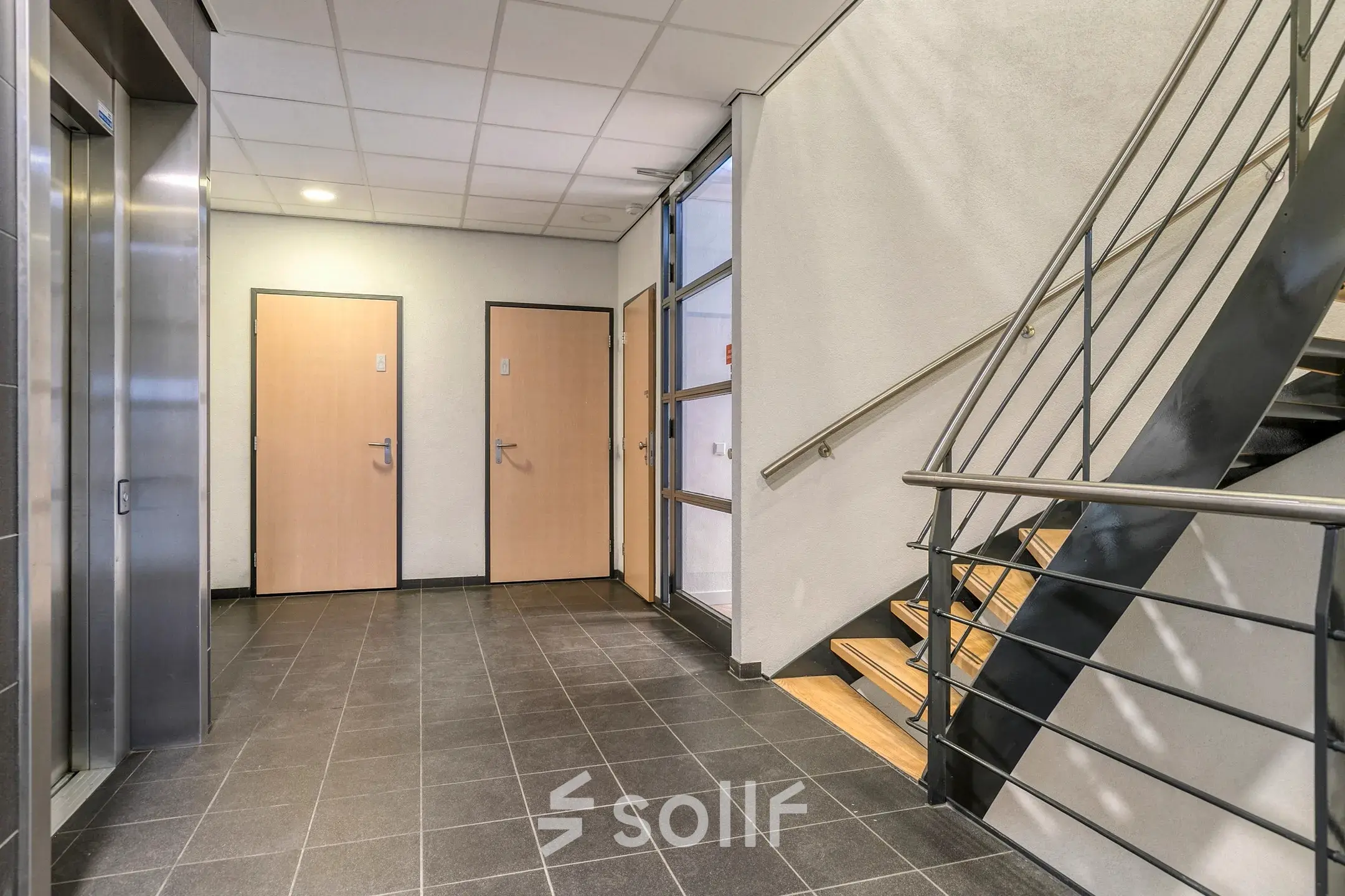 Ingang van kantoorpand Asch van Wijckstraat 2-4 in Amersfoort Centrum met tegelvloer, trap en lift. Kantoorruimte huren in een modern gebouw.