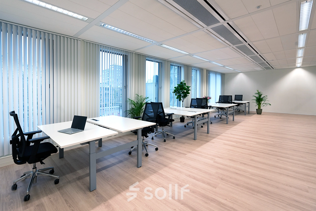 Lichte open werkruimte met moderne bureaus en stoelen, veel natuurlijk licht, ideaal voor kantoorruimte huren aan de Handelsweg 53 in Amstelveen. Planten zorgen voor een frisse ambiance.