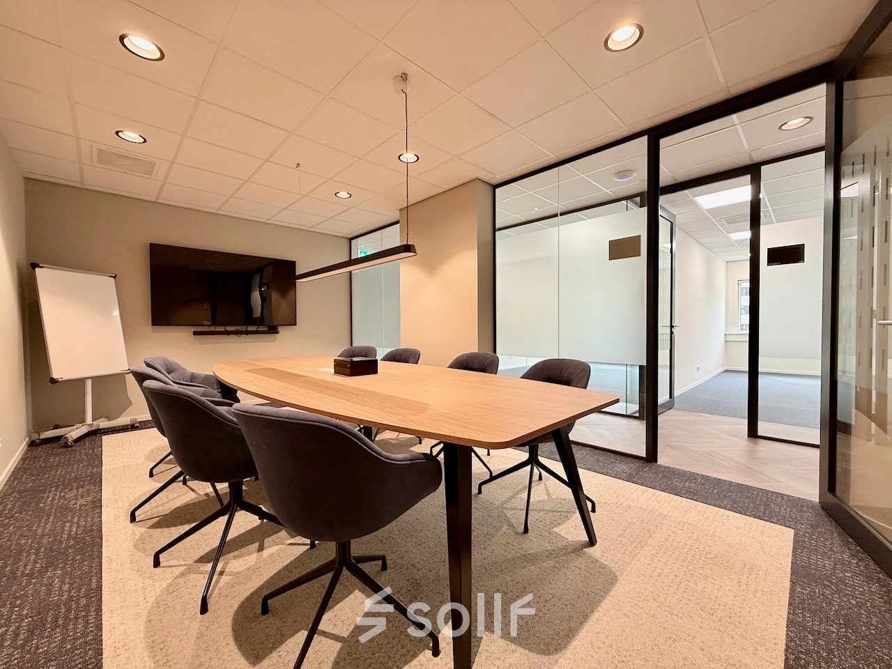 Moderne, goed verlichte vergaderruimte in een kantoorpand aan Professor E.M. Meijerslaan 1, Amstelveen, met comfortabele stoelen rondom een houten tafel en een presentatiescherm.