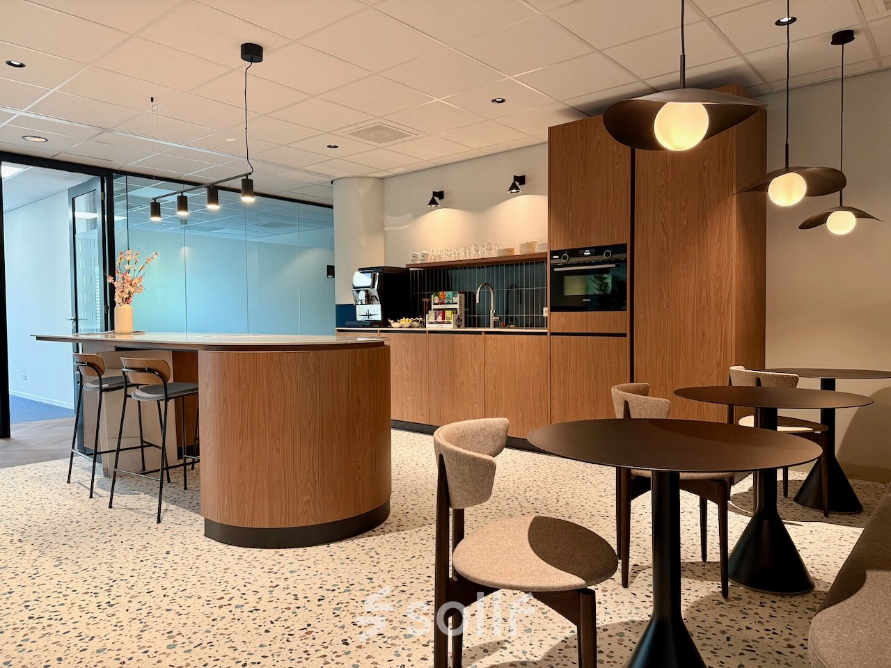 Moderne, lichte kantoorpand pantry op Professor E.M. Meijerslaan 1 in Amstelveen met ronde tafels, barkrukken en ingebouwde keukenapparatuur. Perfect om kantoorruimte te huren voor creatieve pauzemomenten en informele vergaderingen.