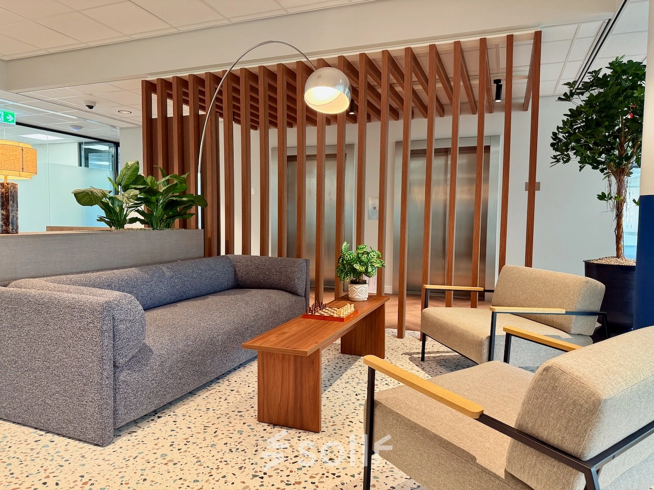 Moderne kantoorruimte aan Professor E.M. Meijerslaan 1 in Amstelveen met comfortabele zitbanken, houten elementen en groene planten, ideaal voor ontspanning en informele gesprekken.