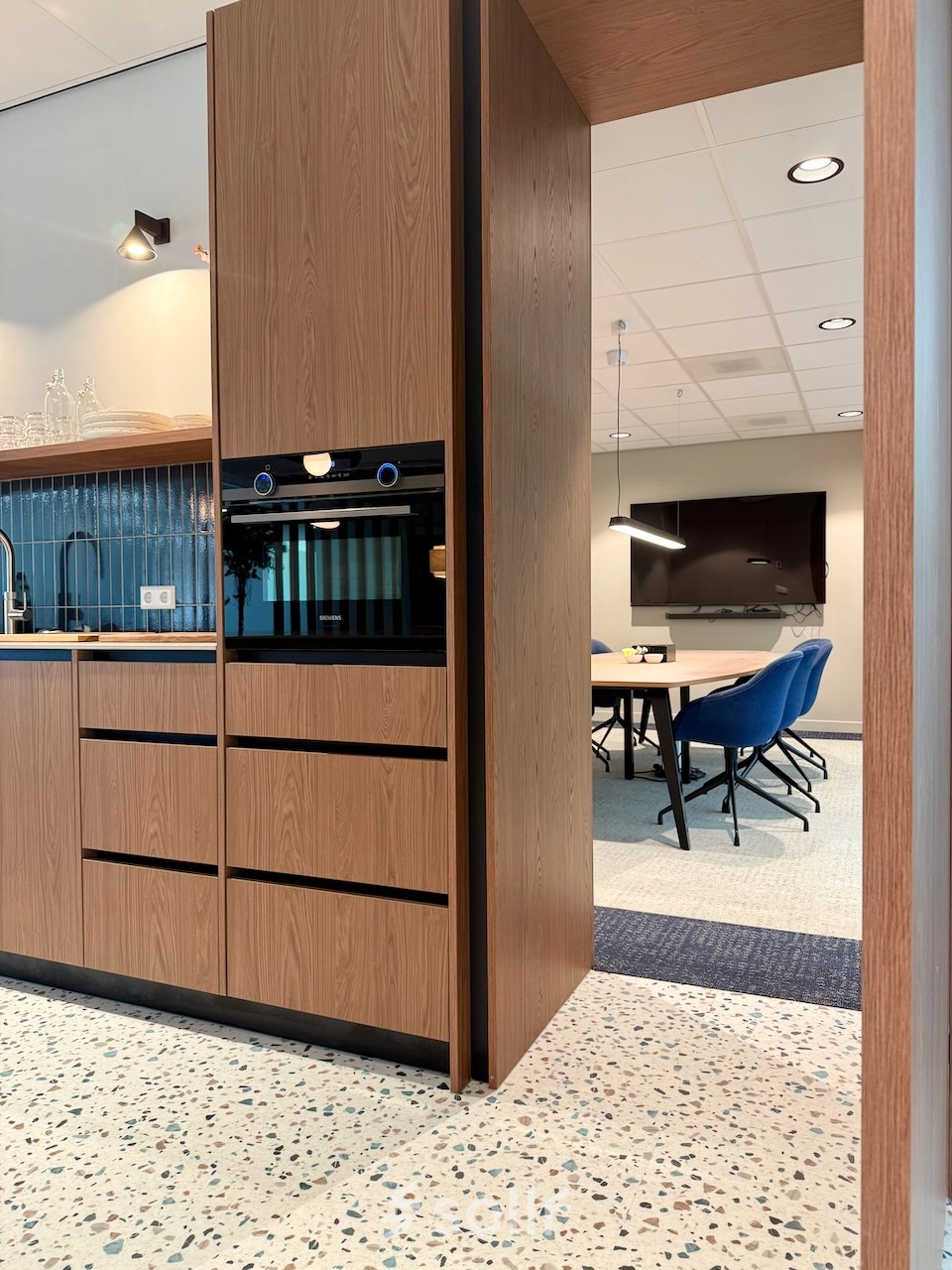 Moderne kantoorruimte met een volledig ingerichte pantry en zicht op een vergadertafel in een functionele kantooromgeving in Amstelveen.