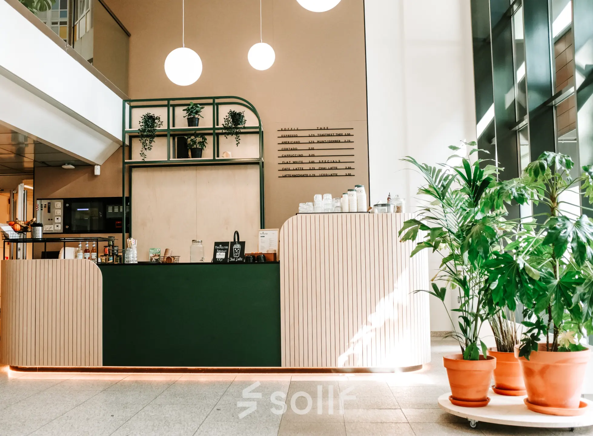 Gezellige lounge in Amstelveen met groentinten, een moderne balie en groene planten bij de ingang van een kantoorpand. Ideale plek voor kantoorruimte huren.