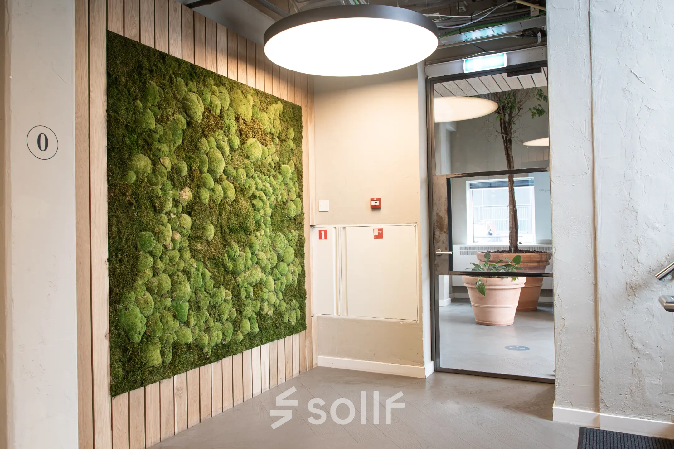 Moderne kantoorruimte in Amsterdam Amstel Business Park met groene muur en grote hanglamp, ideaal voor kantoorruimte huren.