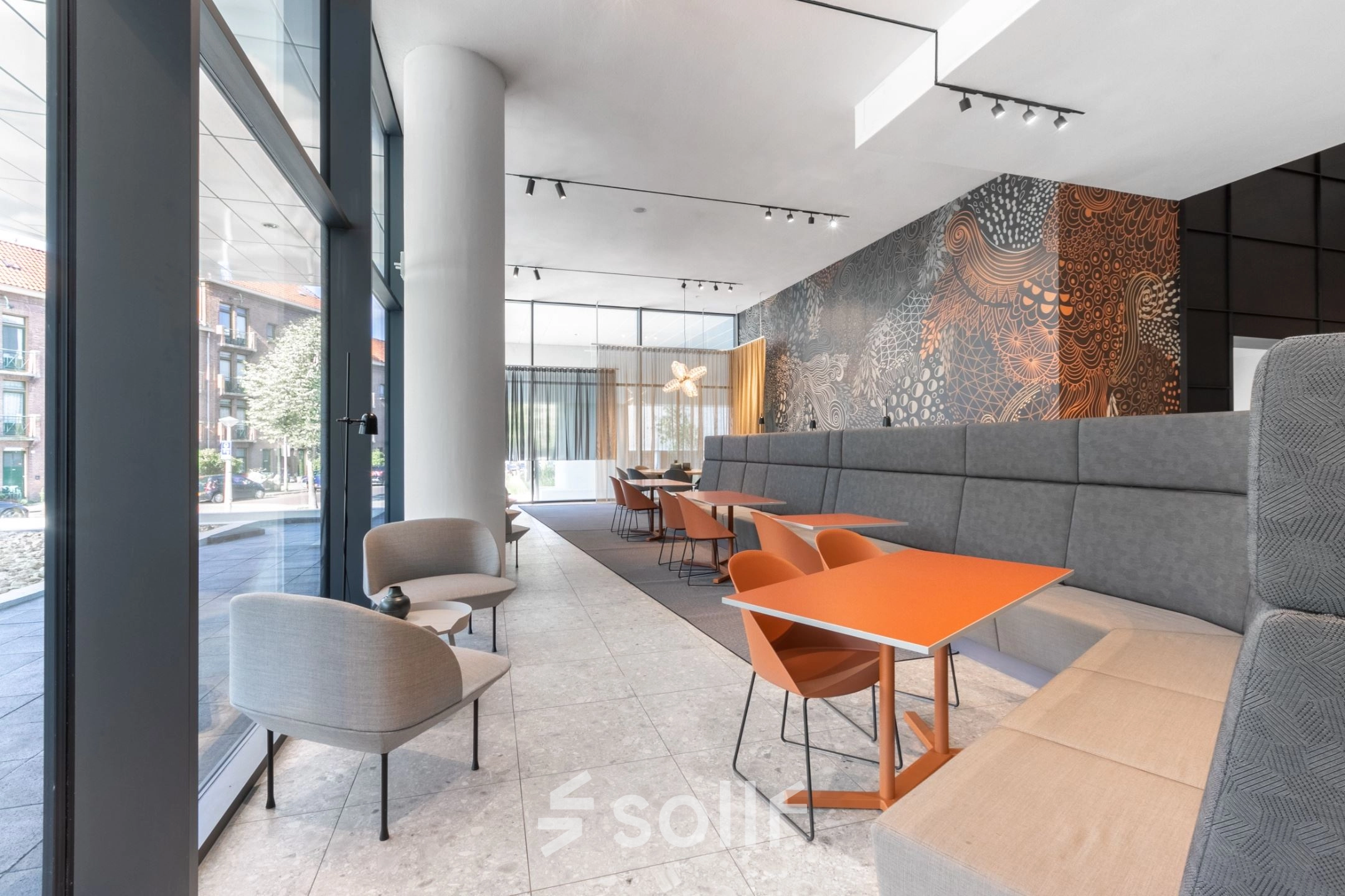 Gezellig ingerichte lounge in het kantoorpand op Trompenburgstraat 2c, Amsterdam Amstel Business Park. Moderne zitruimte met kleurrijke stoelen en veel natuurlijk licht, ideaal voor informeel overleg of pauzes tijdens het werken.