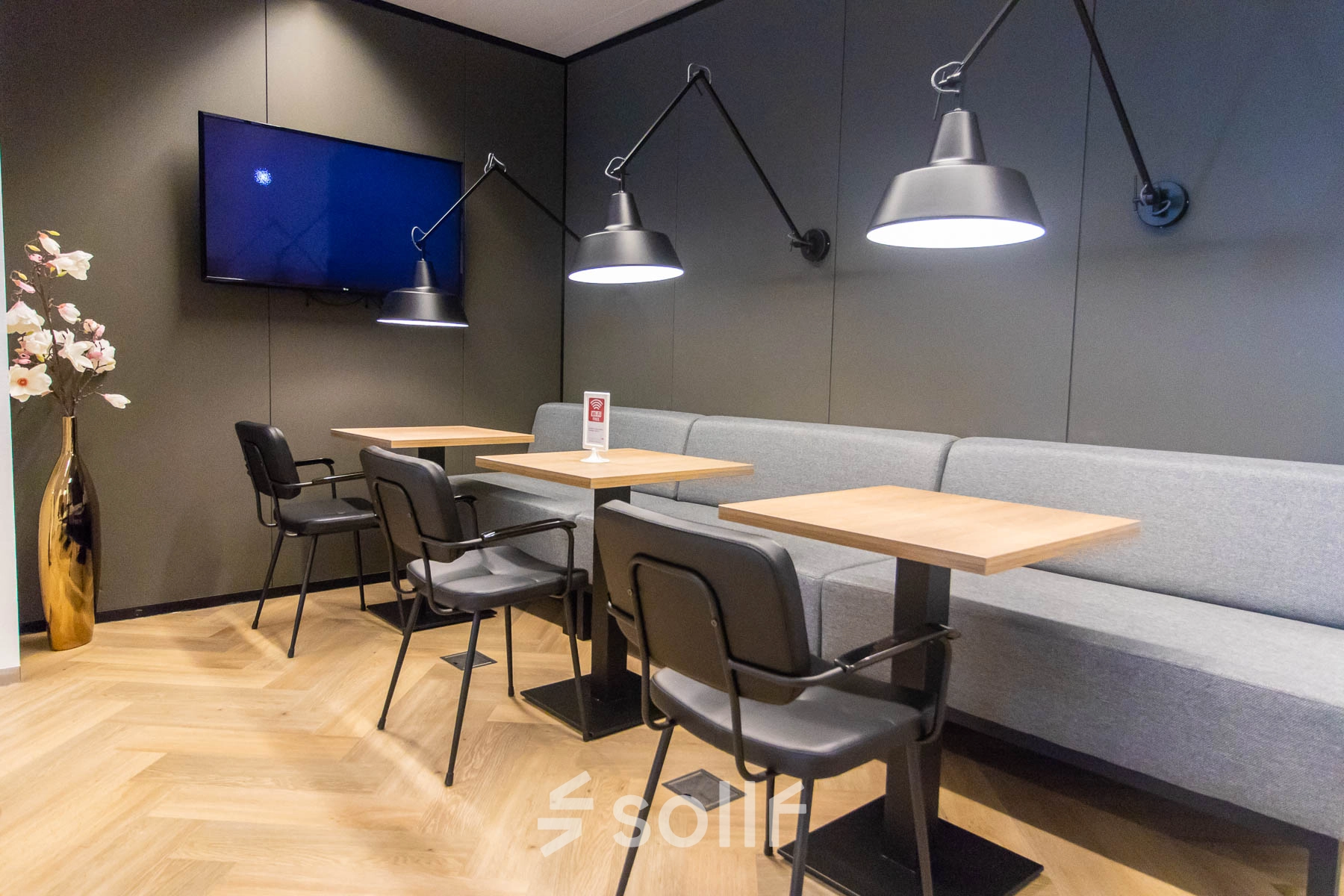 Moderne kantoorruimte met houten vloer en stijlvolle verlichting op Amstelplein 8, Amsterdam Amstel. De ruimte beschikt over tafels en stoelen, perfect voor huur als werkplek of vergaderruimte.