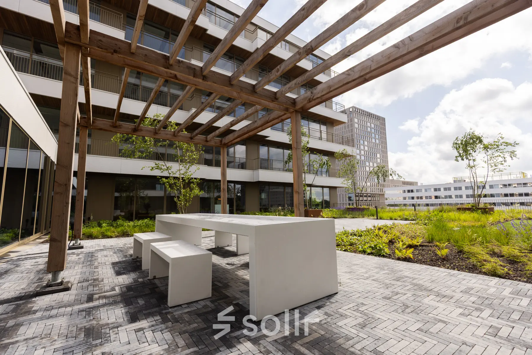 Buitenterras van het kantoorpand op Willem Fenengastraat 16 in Amsterdam Amstel met moderne picknicktafels en groene omgeving.