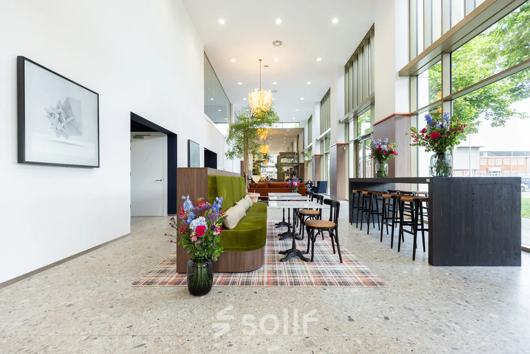 Moderne kantoorruimte met hoge plafonds en veel lichtinval, gelegen aan Willem Fenengastraat 16, Amsterdam Amstel. Ruimte is stijlvol gemeubileerd met banken en hoge tafels, ideaal voor huur als kantoorpand.