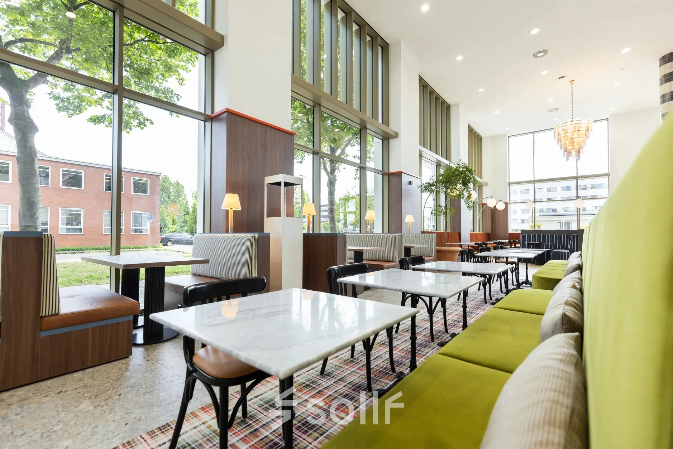 Moderne coworking ruimte huren op Willem Fenengastraat 16 in Amsterdam Amstel met stijlvolle groene en bruine inrichting en grote ramen voor veel natuurlijk licht.