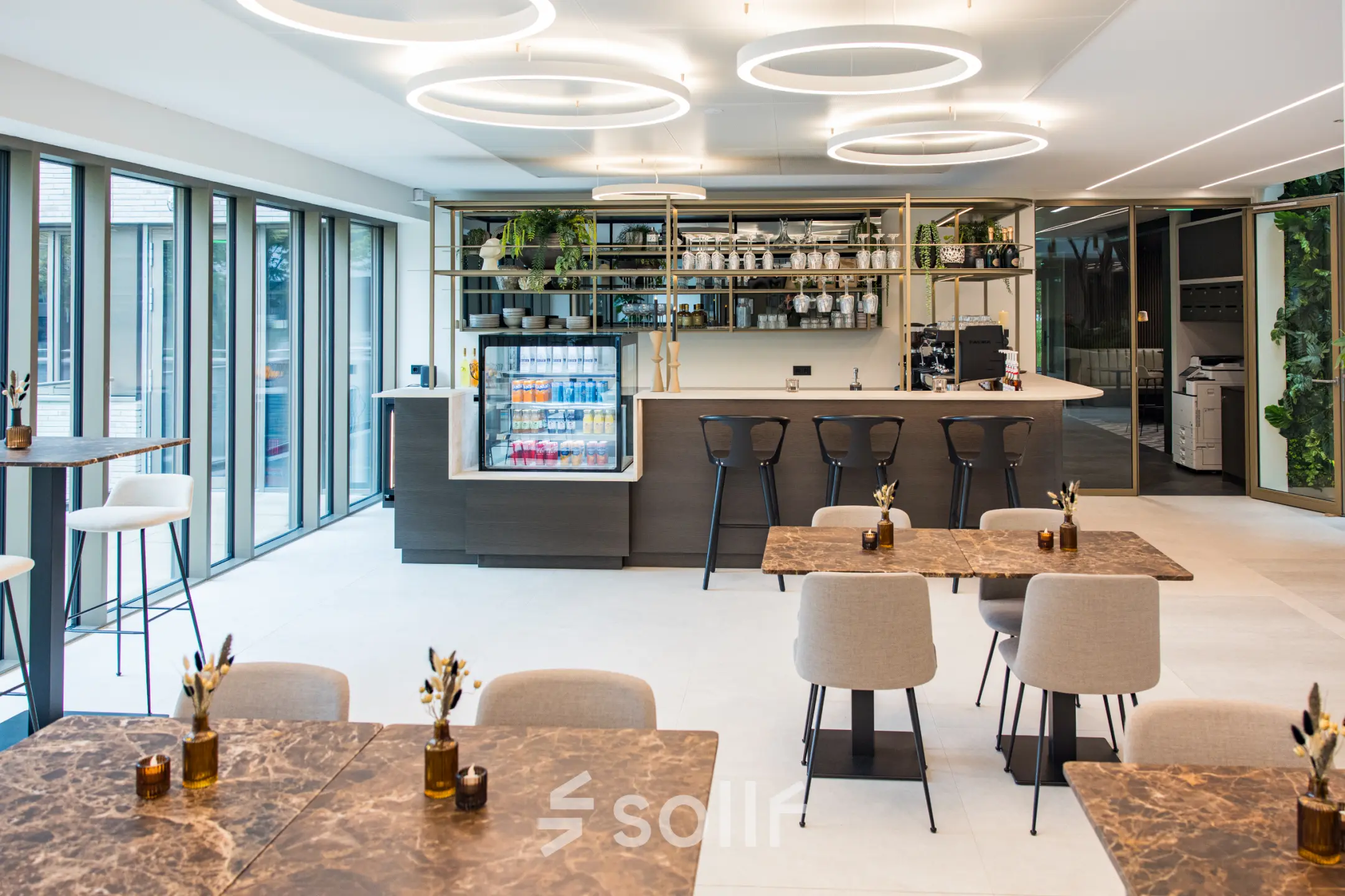 Moderne kantoorpand in Amsterdam Buitenveldert met stijlvolle inrichting en uitnodigende koffiebar. Ideale ruimte voor kantoorruimte huren met lichte tafels en hoge stoelen, klaar voor creativiteit.