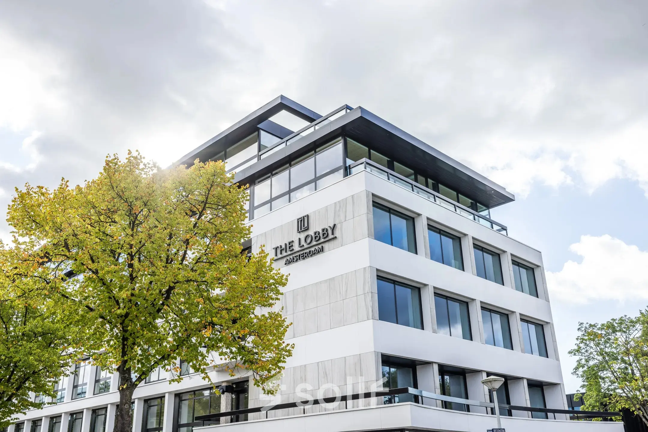 Kantoorpand aan Zwaansvliet 1 in Amsterdam Buitenveldert, modern gebouw met grote ramen en een boom aan de voorzijde. Geschikt voor kantoorruimte huren.