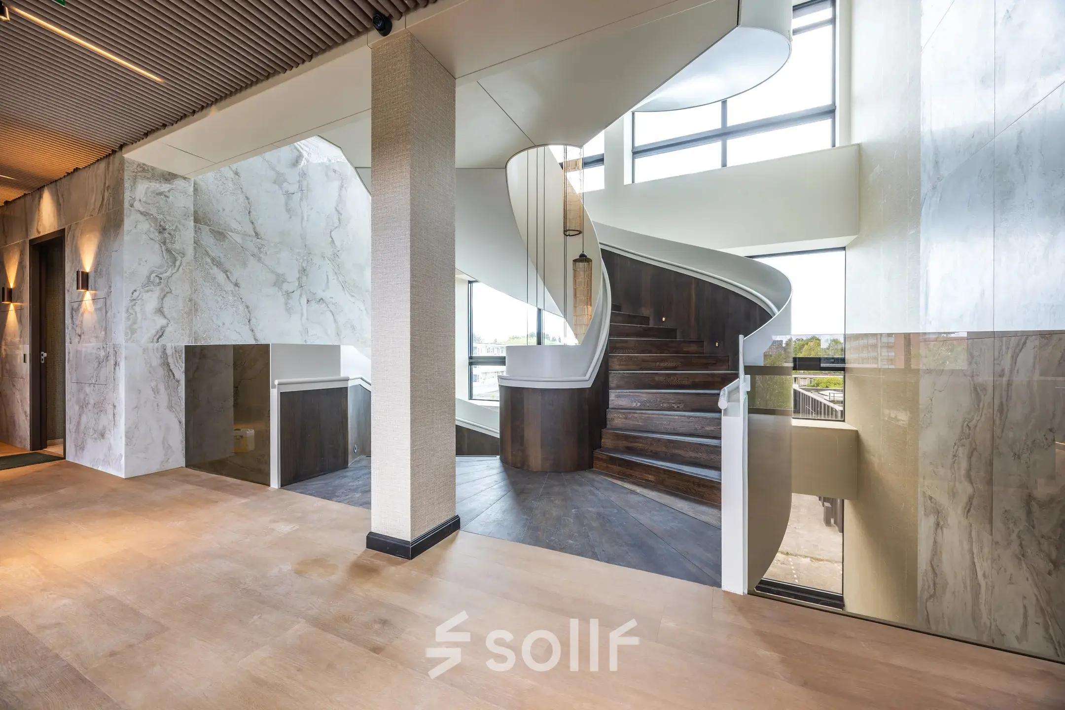 Ruime entree van een kantoorpand aan Zwaansvliet 1 in Amsterdam Buitenveldert, met een opvallende wenteltrap en veel natuurlijk licht. Perfect voor wie kantoorruimte wil huren in een moderne omgeving.