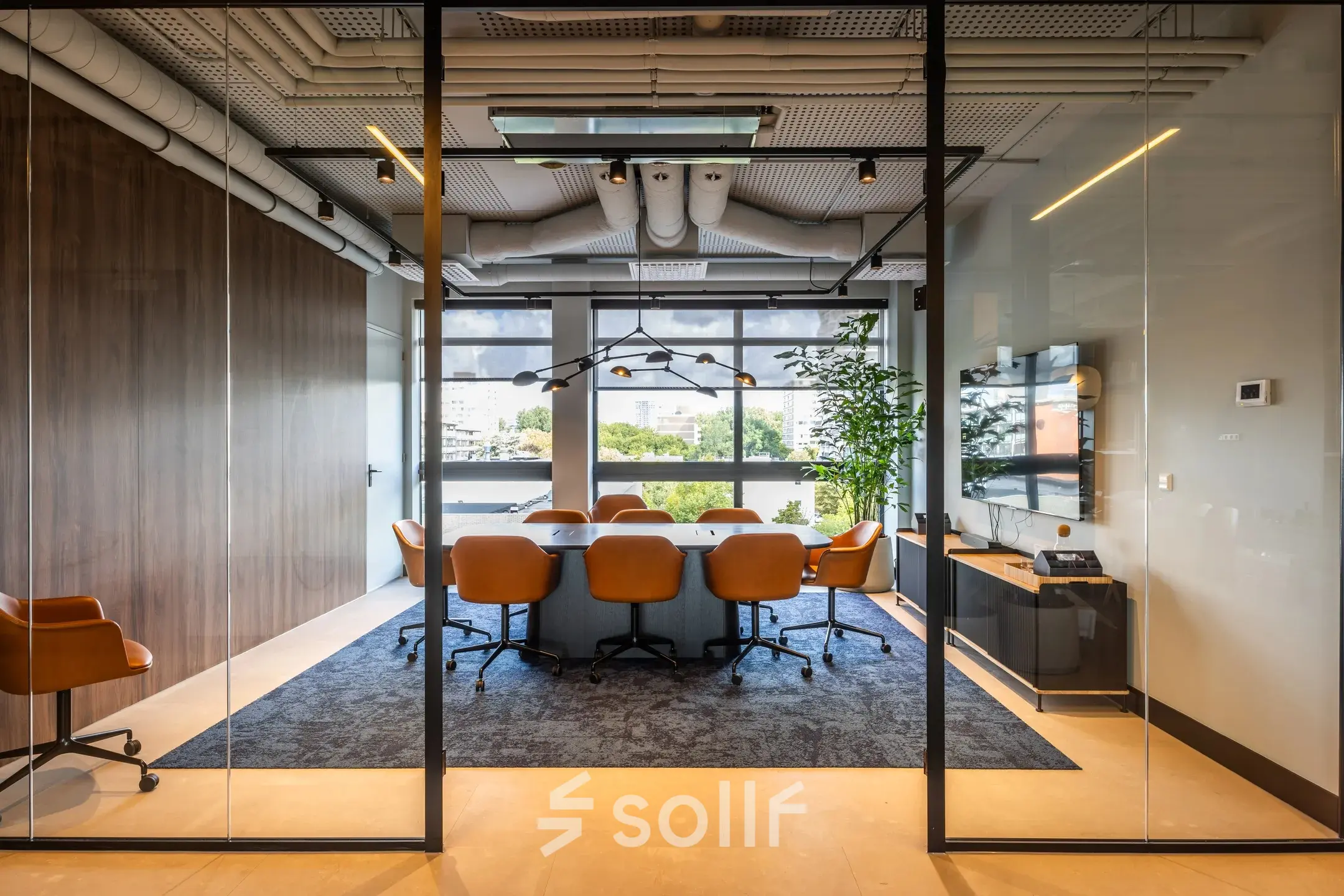 Vergaderruimte in kantoorpand met lange tafel, bruine leren stoelen en groot raam met uitzicht op Amsterdam Buitenveldert. Modern interieur met glazen wanden en houten accenten, geschikt voor kantoorruimte huren.