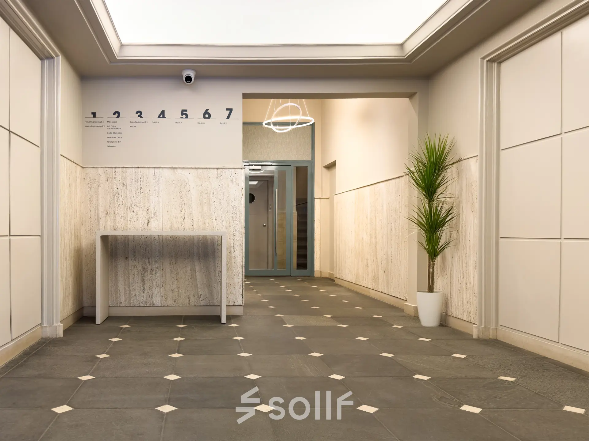 Ingang van een kantoorpand op Kleine Gartmanplantsoen 21 in Amsterdam Centrum met een moderne inrichting en een plant bij de muur.