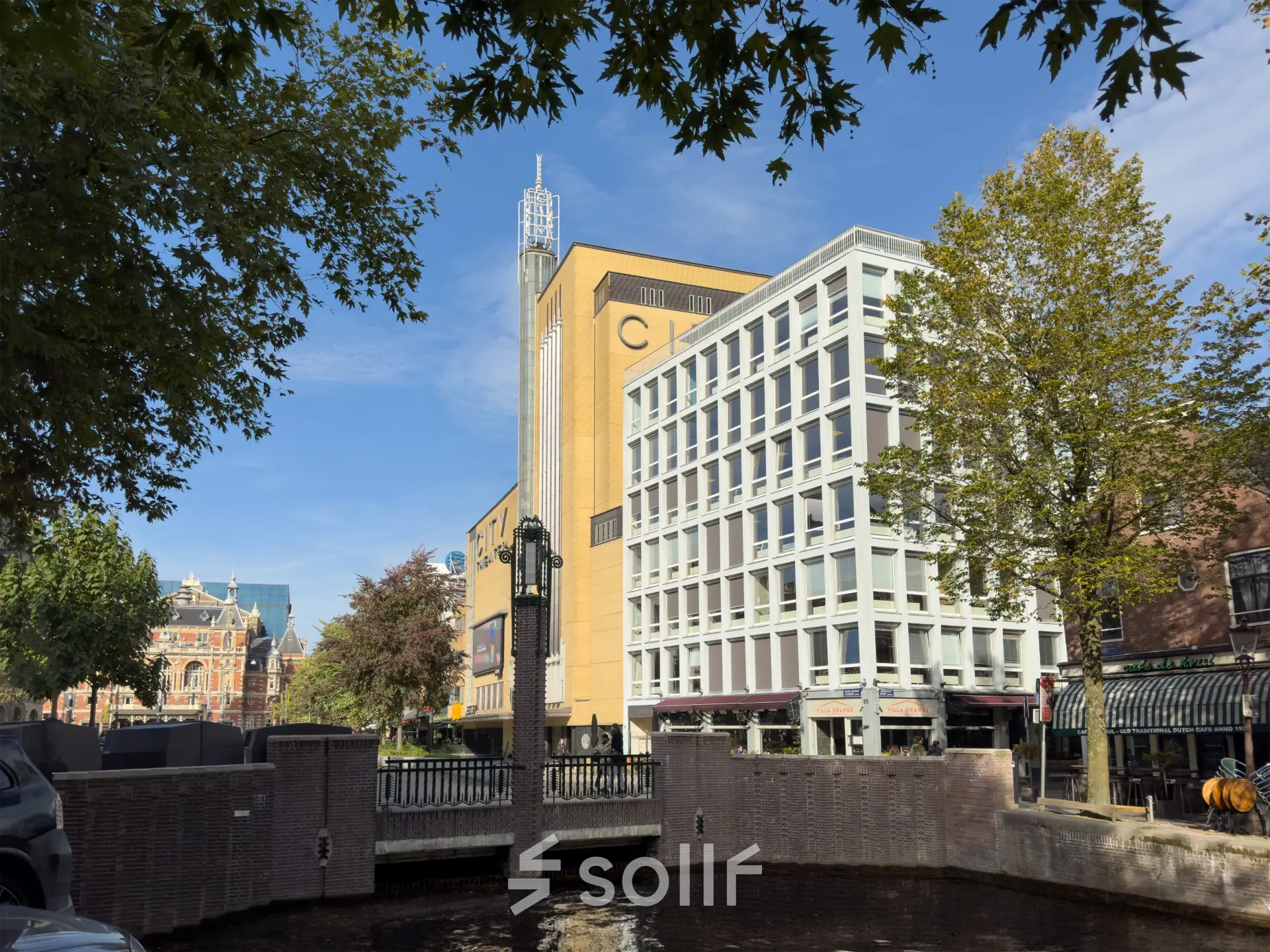 Kantoorpand aan Kleine Gartmanplantsoen 21 in Amsterdam Centrum met moderne gevel en omringd door bomen en water.