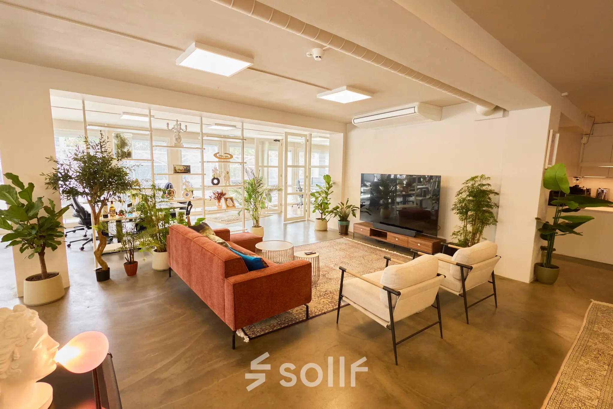 Moderne kantoorruimte huren op Kleine Gartmanplantsoen 21 in Amsterdam Centrum, met een stijlvolle lounge met comfortabele zitplaatsen en planten. Ruimte geschikt voor comfortabel werken en ontspannen.